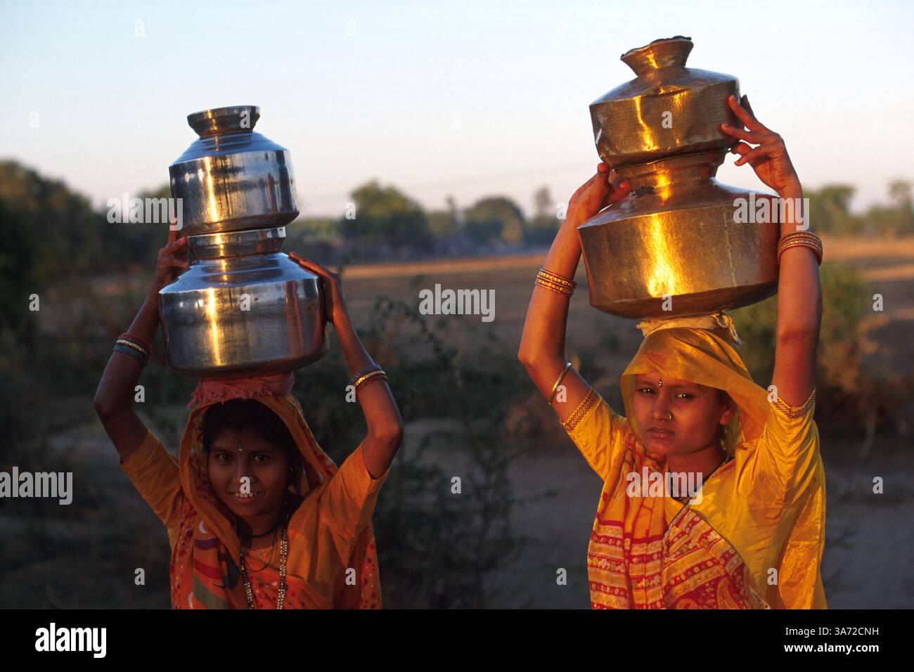 1ER JANVIER 2011 - LES VILLAGEOIS CHARGENT DES CONTENEURS DE LAIT À DESTINATION DES PRODUITS LAITIERS. CES CONTENEURS EN LAITON SONT REMPLIS ET AMENÉS À LA COOPÉRATIVE LAITIÈRE DU VILLAGE DEUX FOIS PAR JOUR, APRÈS LA TRAITE DE SON BÉTAIL. GUJURAT EST UN IMPORTANT PRODUCTEUR DE PRODUITS LAITIERS ET CHOCOLATÉS. ICI, DANS LE VILLAGE DE RUN DANS LA CAMPAGNE DE L'ÉTAT DE GUJURAT, À ENVIRON 60 MILES AU SUD D'AHMEDABAD. CE VILLAGE ABRITE UN PEUPLE BERGER NOMADE TRADITIONNEL QUI EN RAISON DU MANQUE DE TERRES DE PÂTURAGE OG POUR LEUR BÉTAIL SONT DEVENUS PLUS INSTALLÉS.. . K32132PQ Banque D'Images