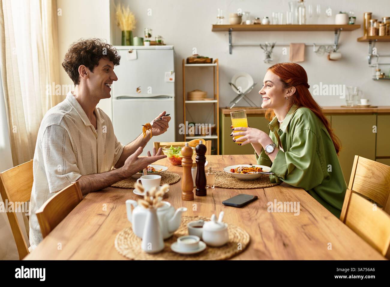 Jeune couple aime un délicieux repas à la maison, partageant des rires et des moments de qualité autour de la nourriture. Banque D'Images