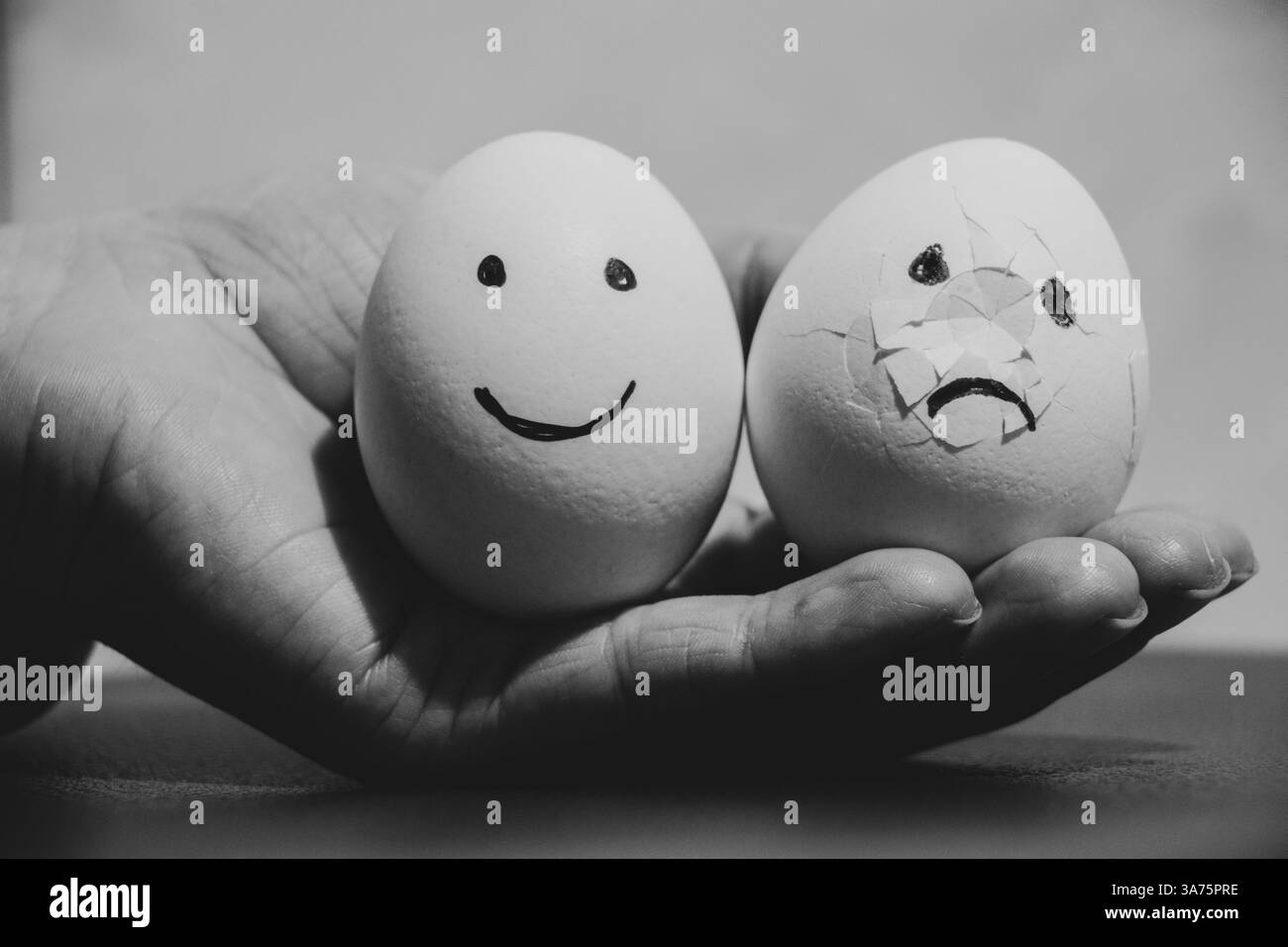 Deux œufs de poule, l'un avec joie et l'autre brisé avec une émotion triste dans la main de la fille, la tristesse et la tristesse Banque D'Images