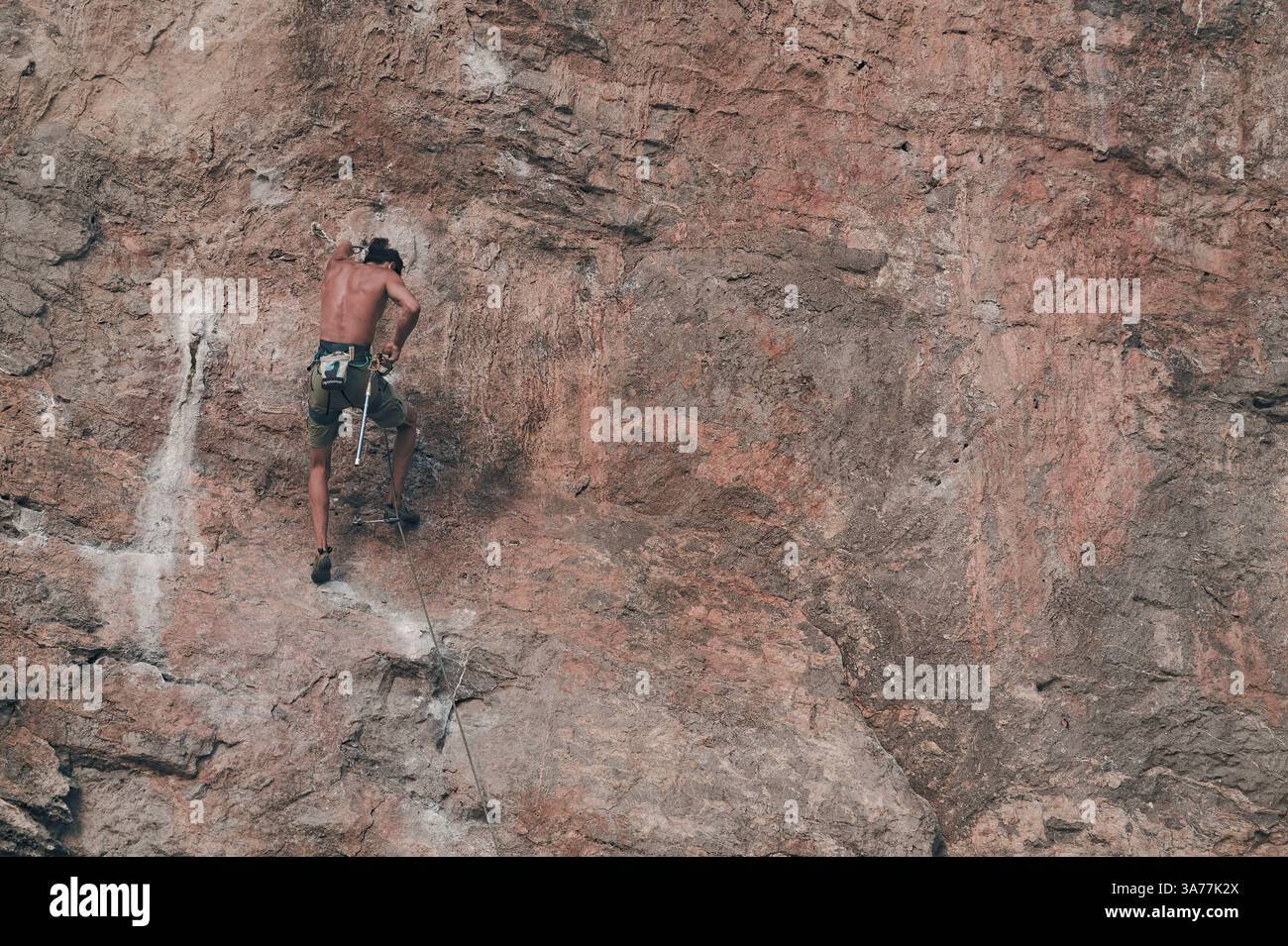 Grimpeur bloqué en concentration tout en s'attaquant à une face calcaire escarpée à Tonsai Banque D'Images