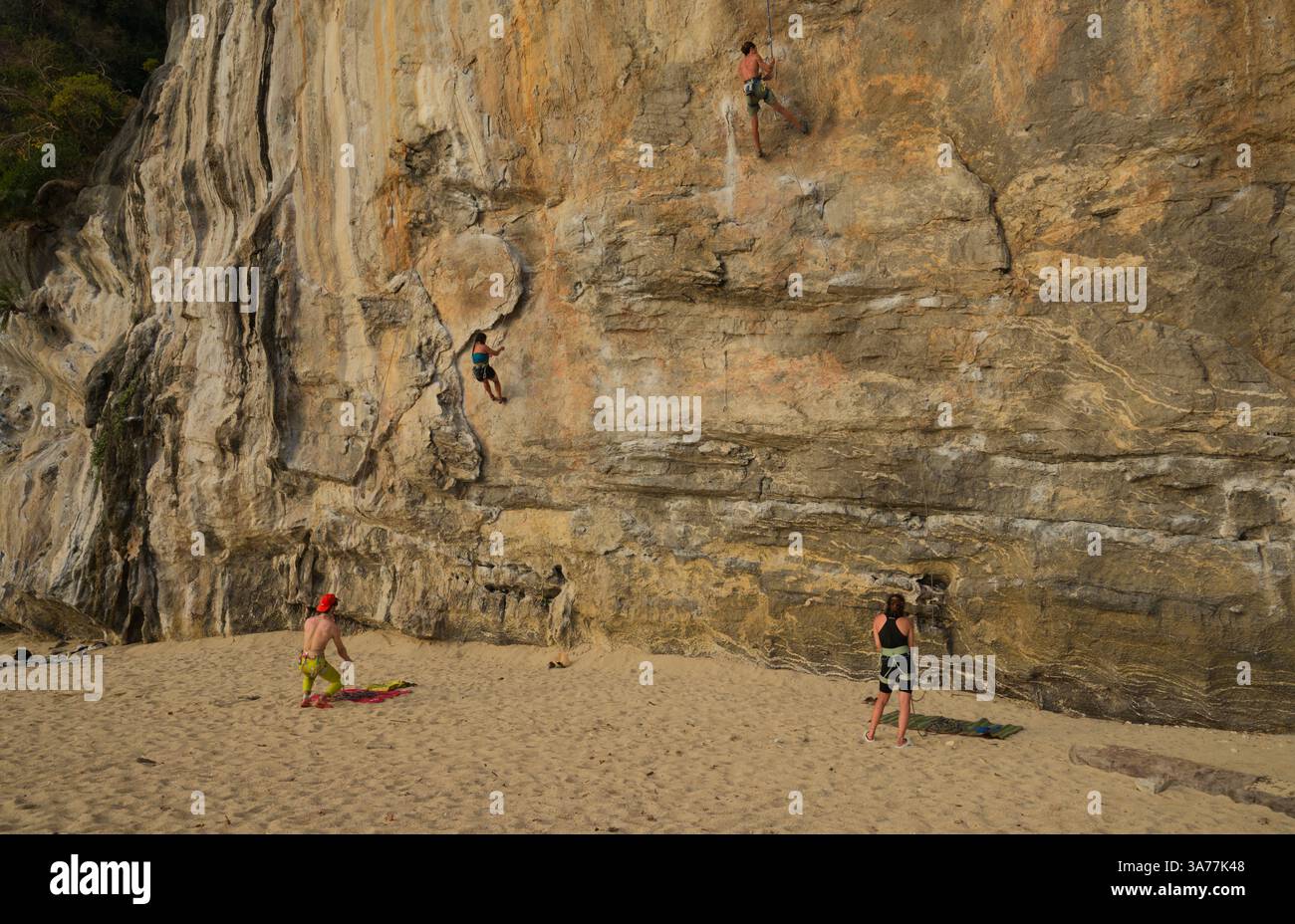 Les grimpeurs escaladent les superbes falaises calcaires de Tonsai, tandis que les gardiens veillent sur le sable Banque D'Images