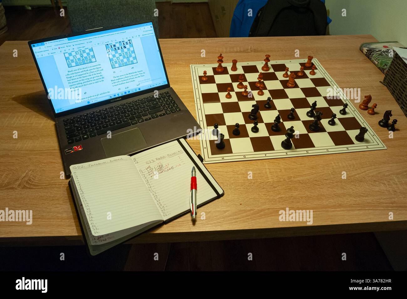 Solitaire entraînement aux échecs avec un ordinateur et de vraies pièces en bois sur un échiquier. Banque D'Images