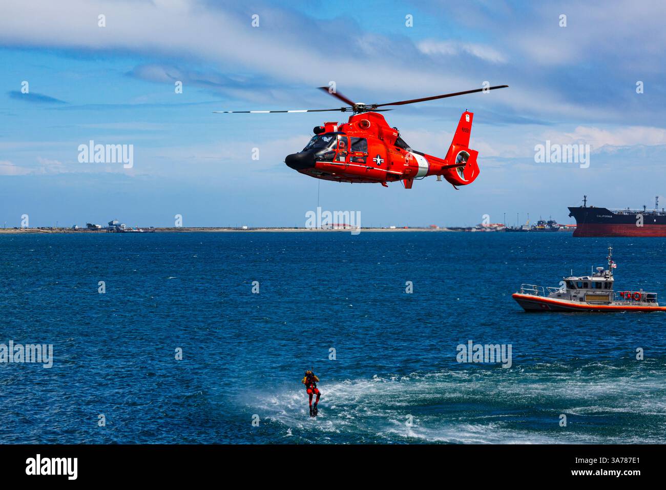 Hélicoptère de la Garde côtière AMÉRICAINE planant au-dessus de l'eau dans une démonstration d'un sauvetage pour un nageur de mer. Banque D'Images