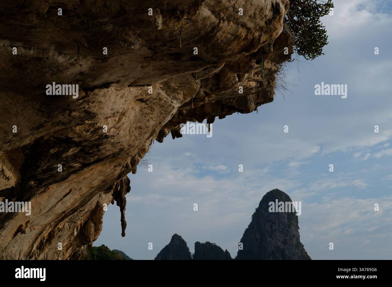 Des boulons et des élingues pendent d'un surplomb déchiqueté à Tonsai, des sommets calcaires emblématiques s'élevant au loin Banque D'Images