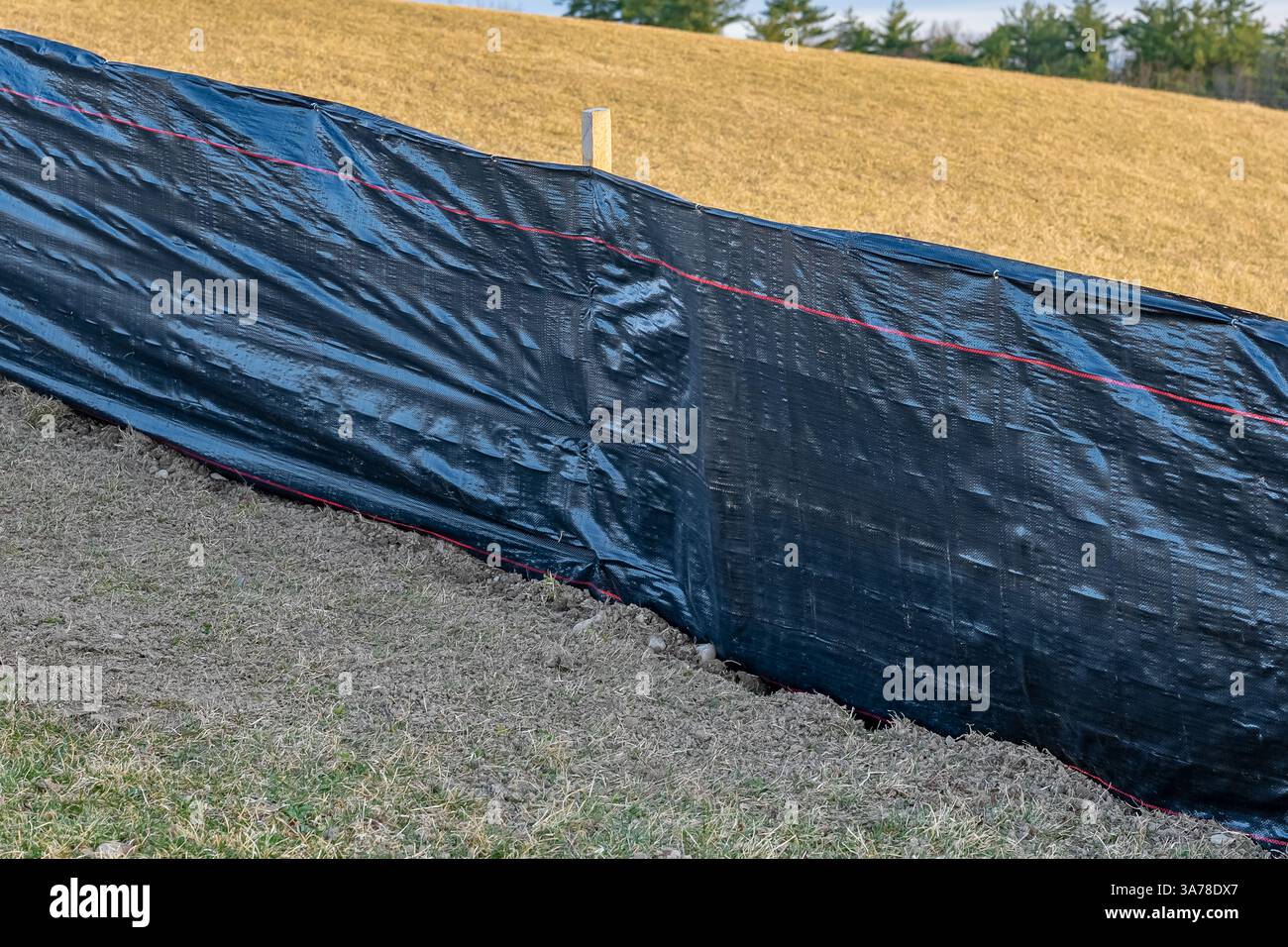 Tissu de clôture de limon avec treillis métallique et poteaux en bois installés avant le début de la construction. Banque D'Images