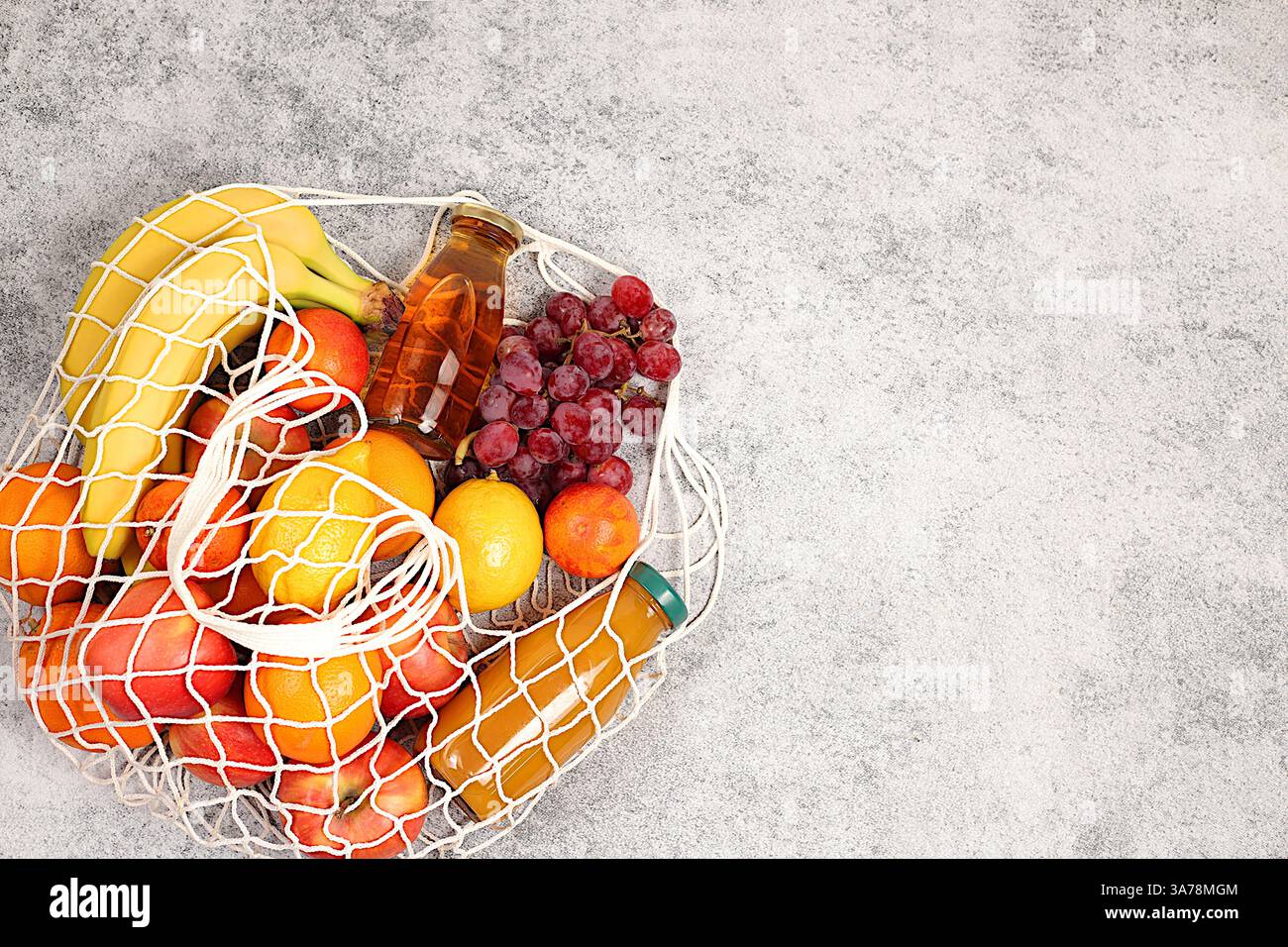 Citrons, oranges, tomates, pommes, bananes, raisins et jus naturels dans un sac réutilisable, sac de ficelle en tissu avec des produits végétaliens sains pour la perte de poids. Banque D'Images