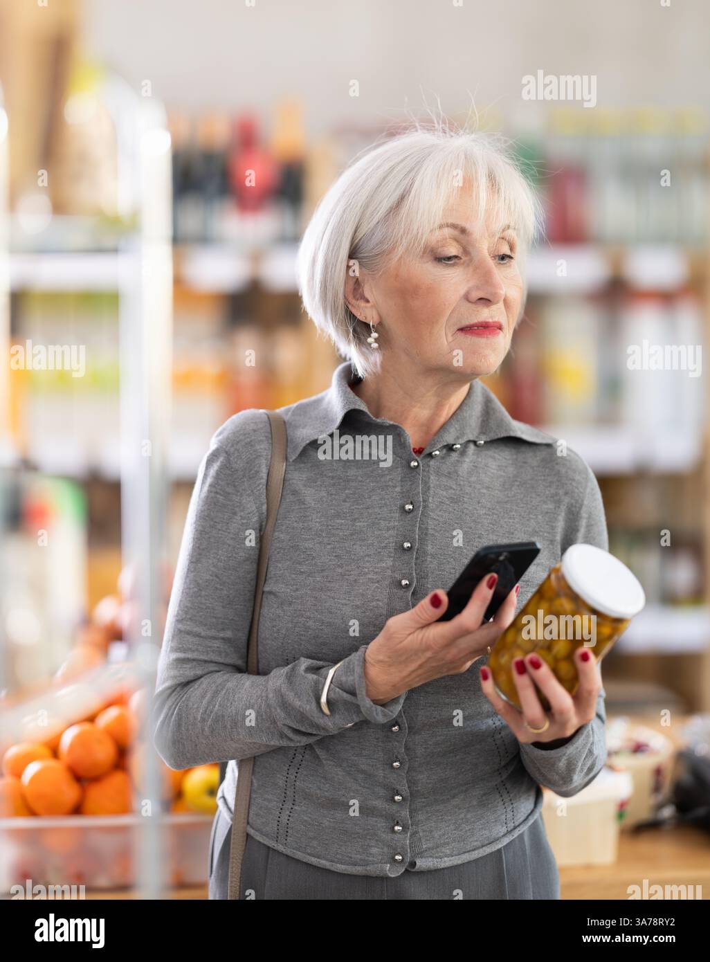 Femme âgée scannant le code qr pour les olives Banque D'Images