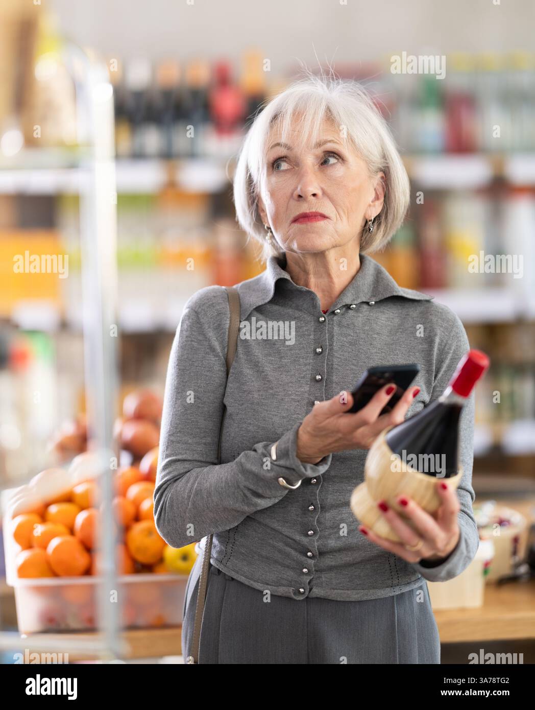 Femme âgée scannant le code qr du vin Banque D'Images