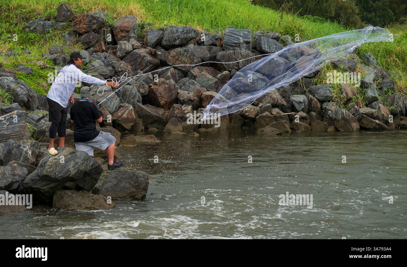 Des pêcheurs non identifiés jetant là un filet pour attraper des appâts vivants à placer sur l'hameçon pour attraper des poissons plus gros. Gold Coast, Queensland, Australie. Banque D'Images