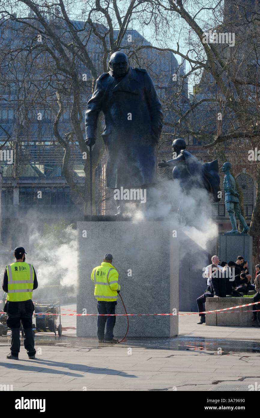 Les ouvriers utilisent un jet d'eau sous pression pour nettoyer l'étaue de Winston Churchill sur la place du Parlement. Banque D'Images