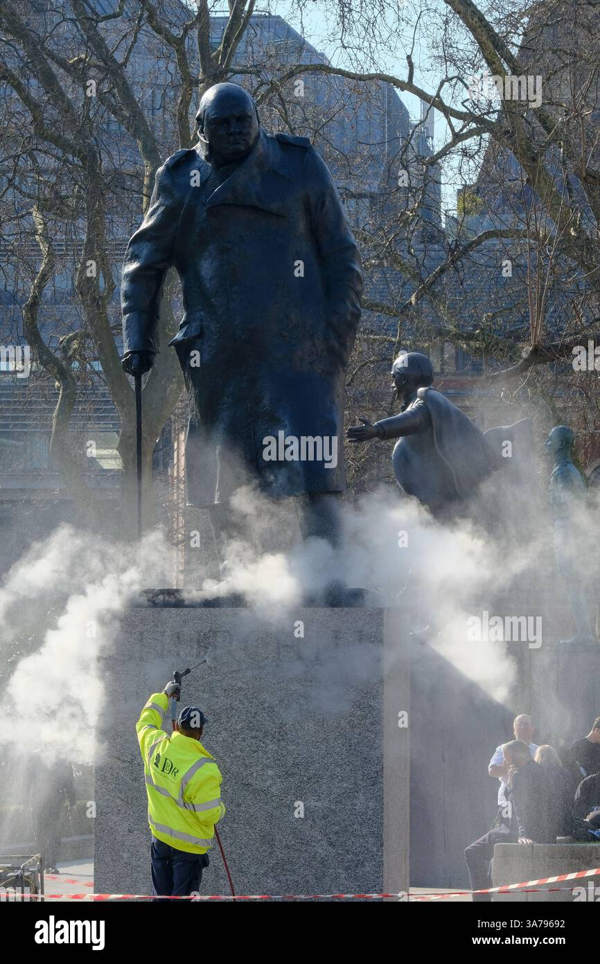 Les ouvriers utilisent un jet d'eau sous pression pour nettoyer l'étaue de Winston Churchill sur la place du Parlement. Banque D'Images
