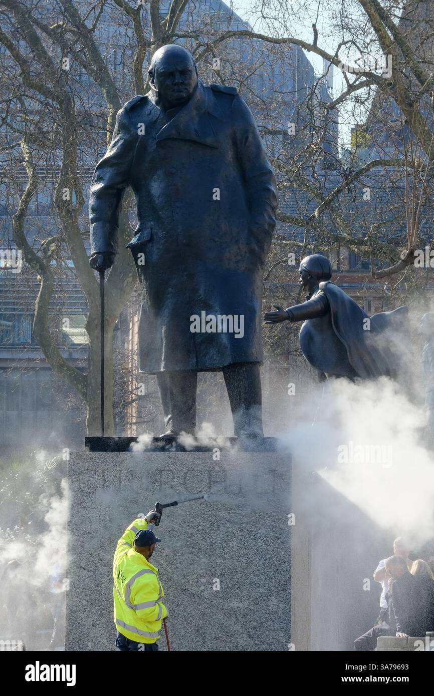 Les ouvriers utilisent un jet d'eau sous pression pour nettoyer l'étaue de Winston Churchill sur la place du Parlement. Banque D'Images