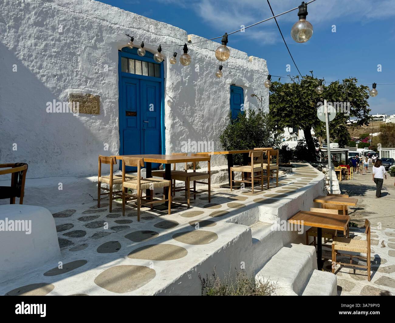Tables et chaises sur la terrasse d'une taverne fermée dans le paisible village intérieur d'Ano Mera, sur l'île de Mykonos, en Grèce. - Image de stock capturée avec un smartphone