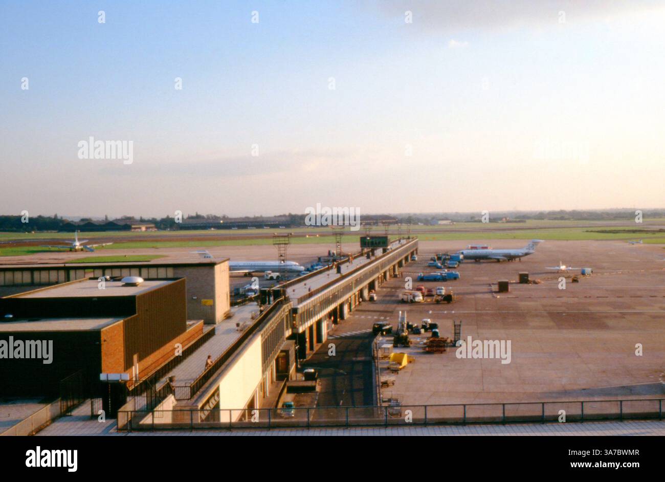 Une vue de l'aéroport de Manchester dans les années 1970, montrant le tablier principal du terminal avec des avions de l'époque garés et en cours d'entretien. Les passagers peuvent être vus marcher le long de la plate-forme d'observation extérieure, une caractéristique commune de l'aéroport de l'époque. Banque D'Images