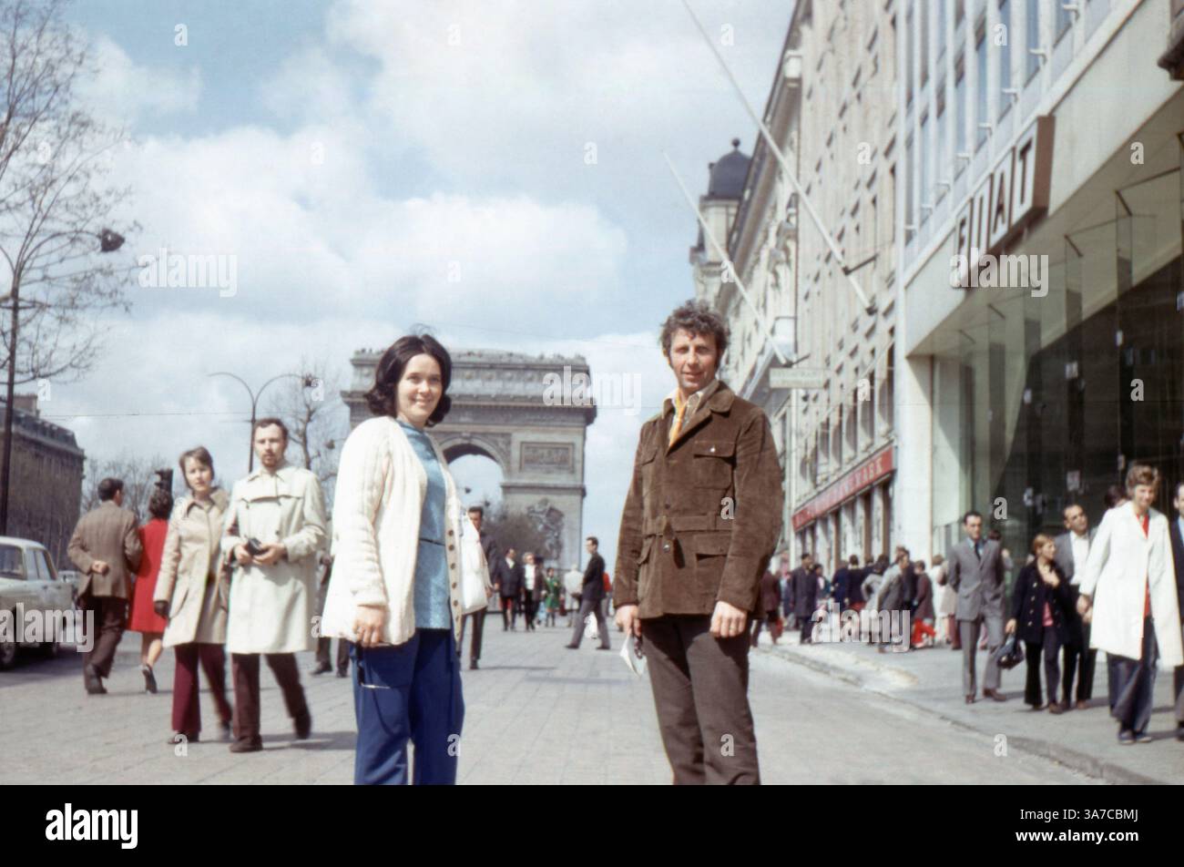 Une scène de rue animée des années 1960 sur les champs-Élysées à Paris, en France, avec piétons et touristes avec l'Arc de Triomphe en arrière-plan. Une importante concession FIAT occupe le côté droit du châssis, reflétant le boom de la culture automobile européenne et du commerce urbain d'après-guerre au cœur de la capitale française. Banque D'Images