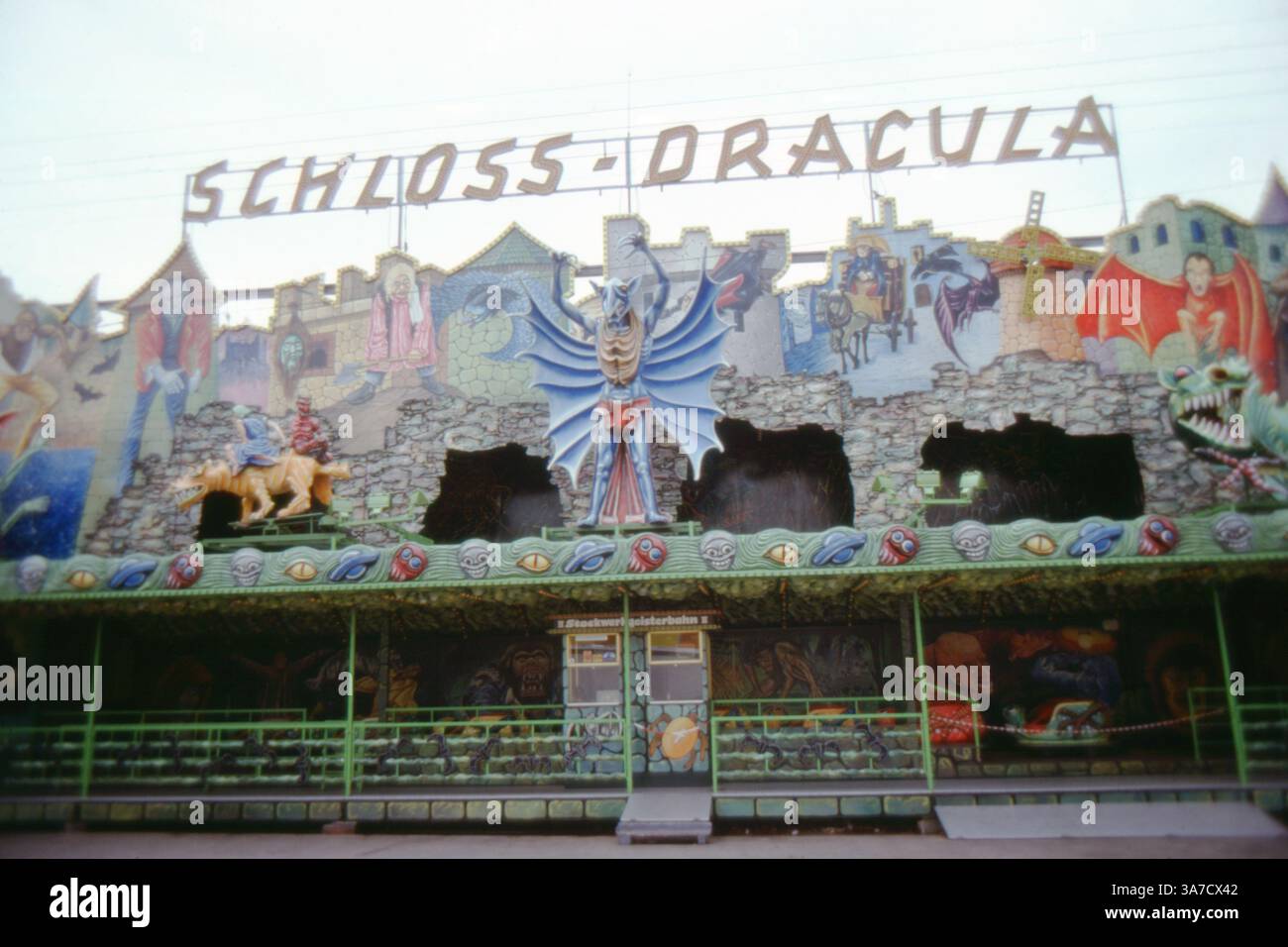 Une photo vibrante de 1979 de la maison hantée « Schloss Dracula » à la foire Schützfest à Hanovre, en Allemagne. La façade élaborée présente des peintures murales sur le thème de l'horreur comprenant des vampires, des squelettes, des monstres et des créatures mythiques Banque D'Images