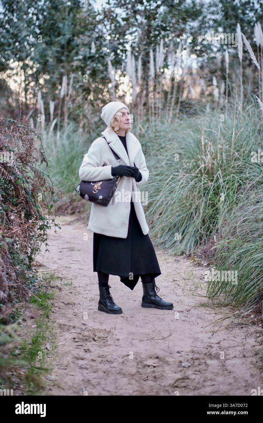 Femme âgée portant des vêtements d'hiver marchant dans un parc en cantabrie, en espagne, pendant une journée ensoleillée d'hiver Banque D'Images