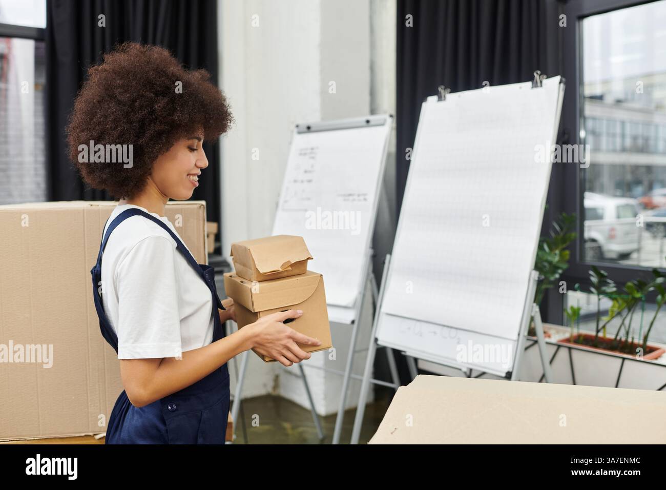 Un ouvrier transporte soigneusement de petites boîtes tout en organisant un bureau contemporain lors de la réinstallation. Banque D'Images
