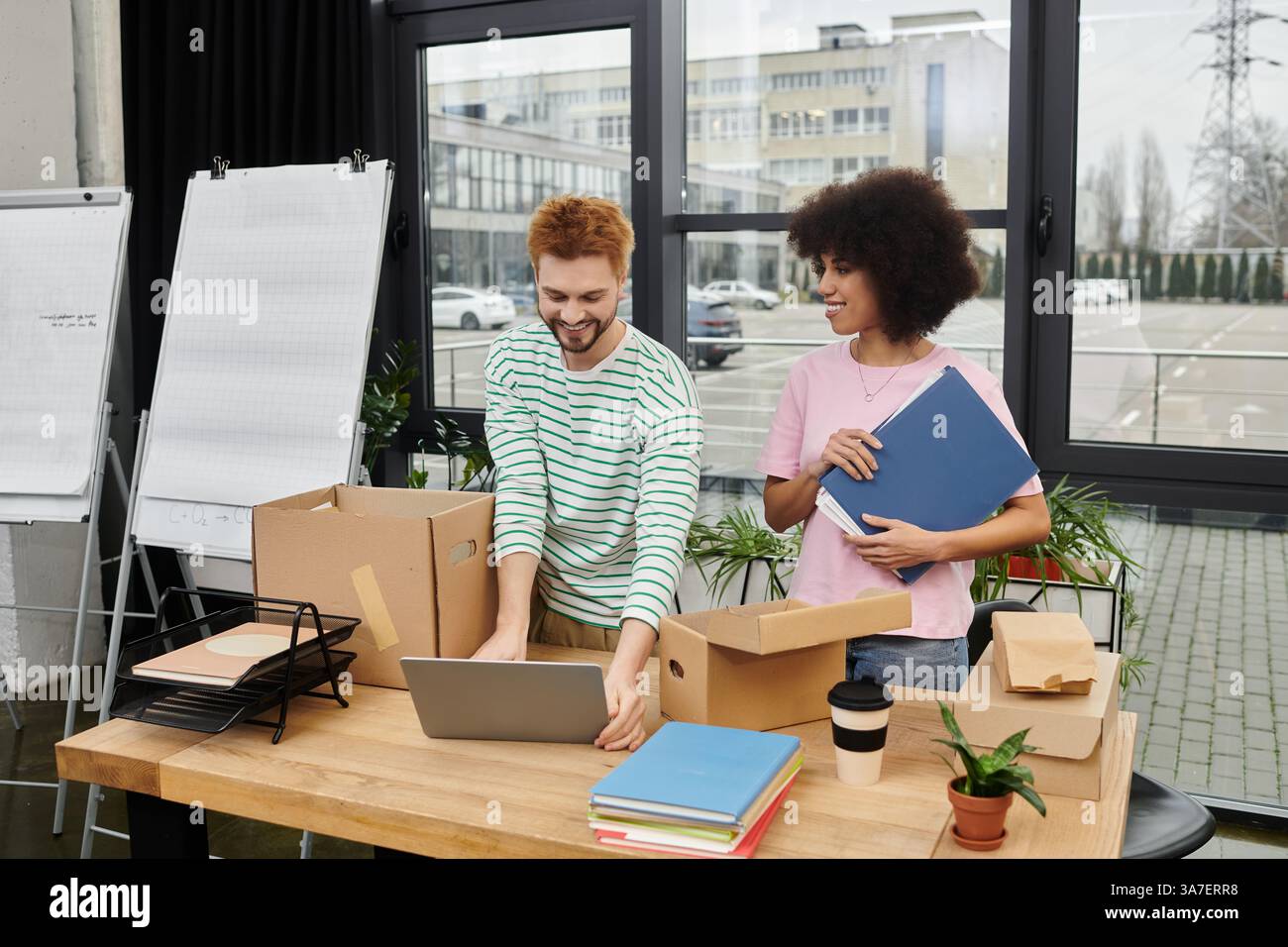 Les individus se concentrent sur leurs tâches d'organisation et de déballage dans un environnement de bureau contemporain. Banque D'Images