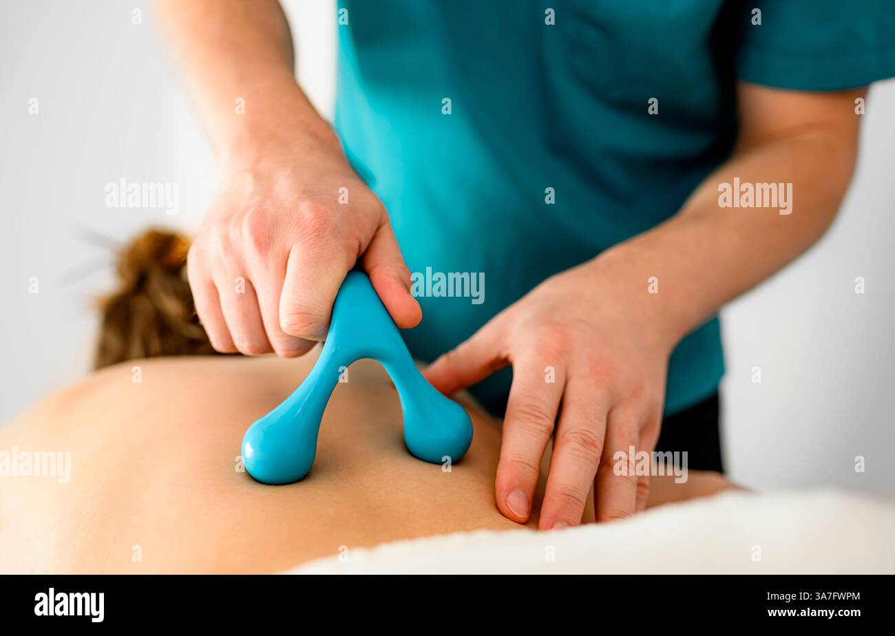 Masseur professionnel faisant massage du dos avec des accessoires de massage spéciaux dans un salon de massage Banque D'Images