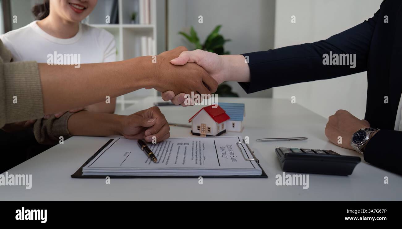 Accord de clôture et d'affaires. Un couple serre la main à son agent immobilier après avoir conclu la vente. Banque D'Images