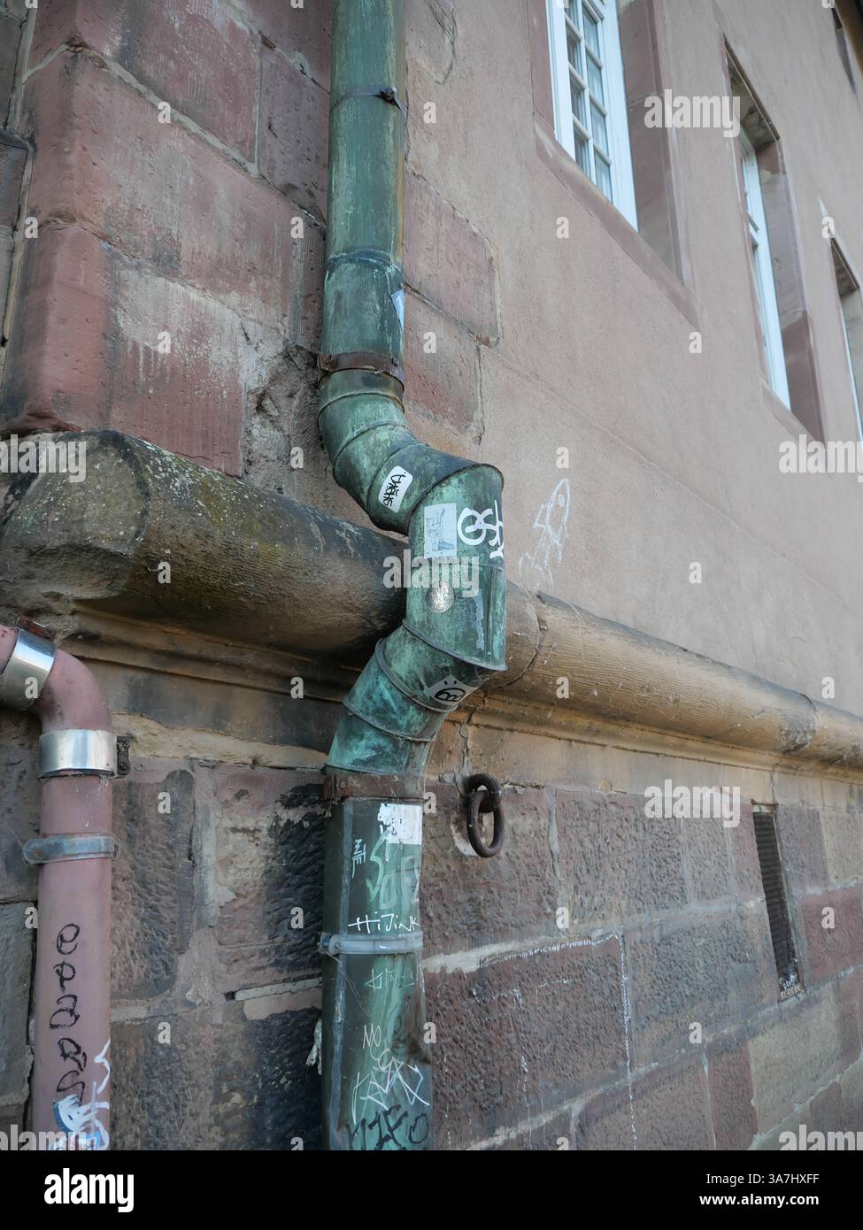 La descente d’un système de drainage de toiture est façonnée autour d’un rebord en pierre à Strasbourg (Alsace, France) Banque D'Images