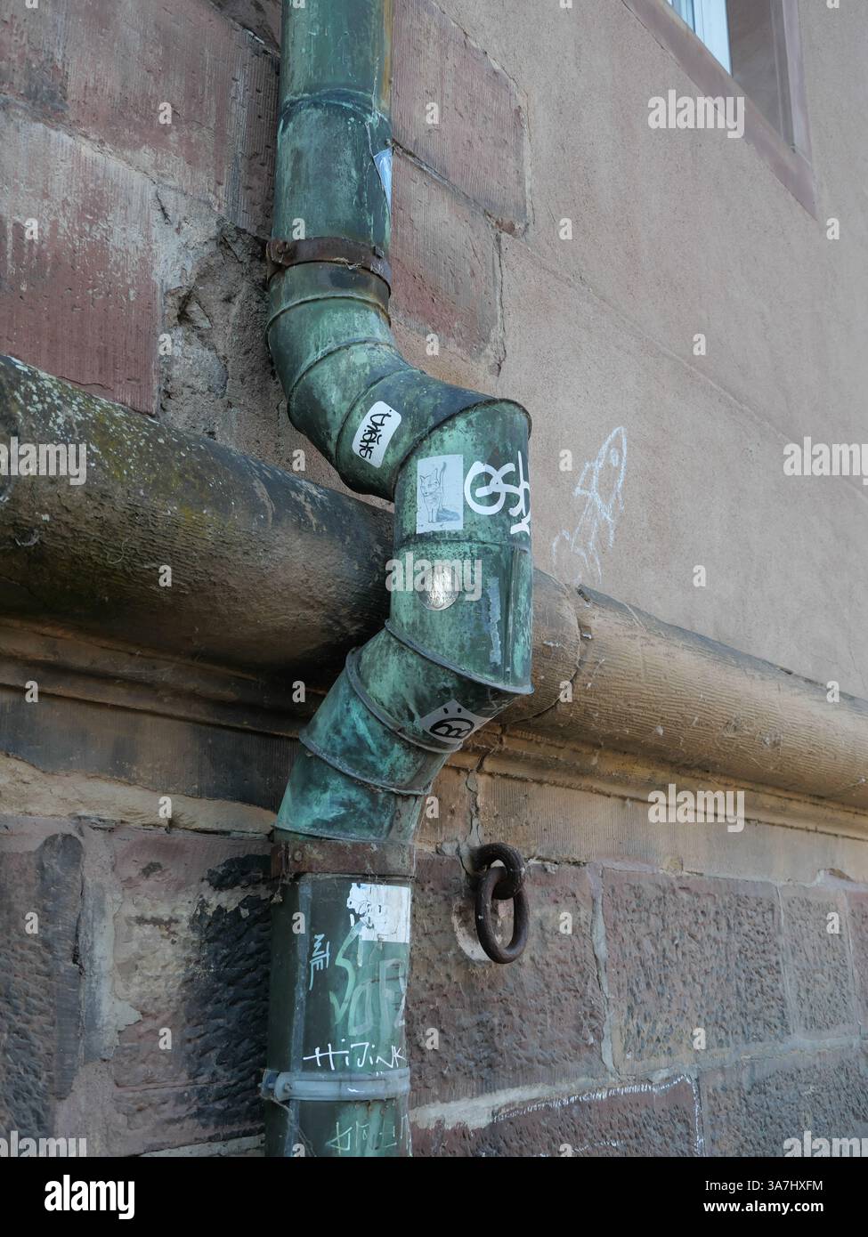 La descente d’un système de drainage de toiture est façonnée autour d’un rebord en pierre à Strasbourg (Alsace, France) Banque D'Images