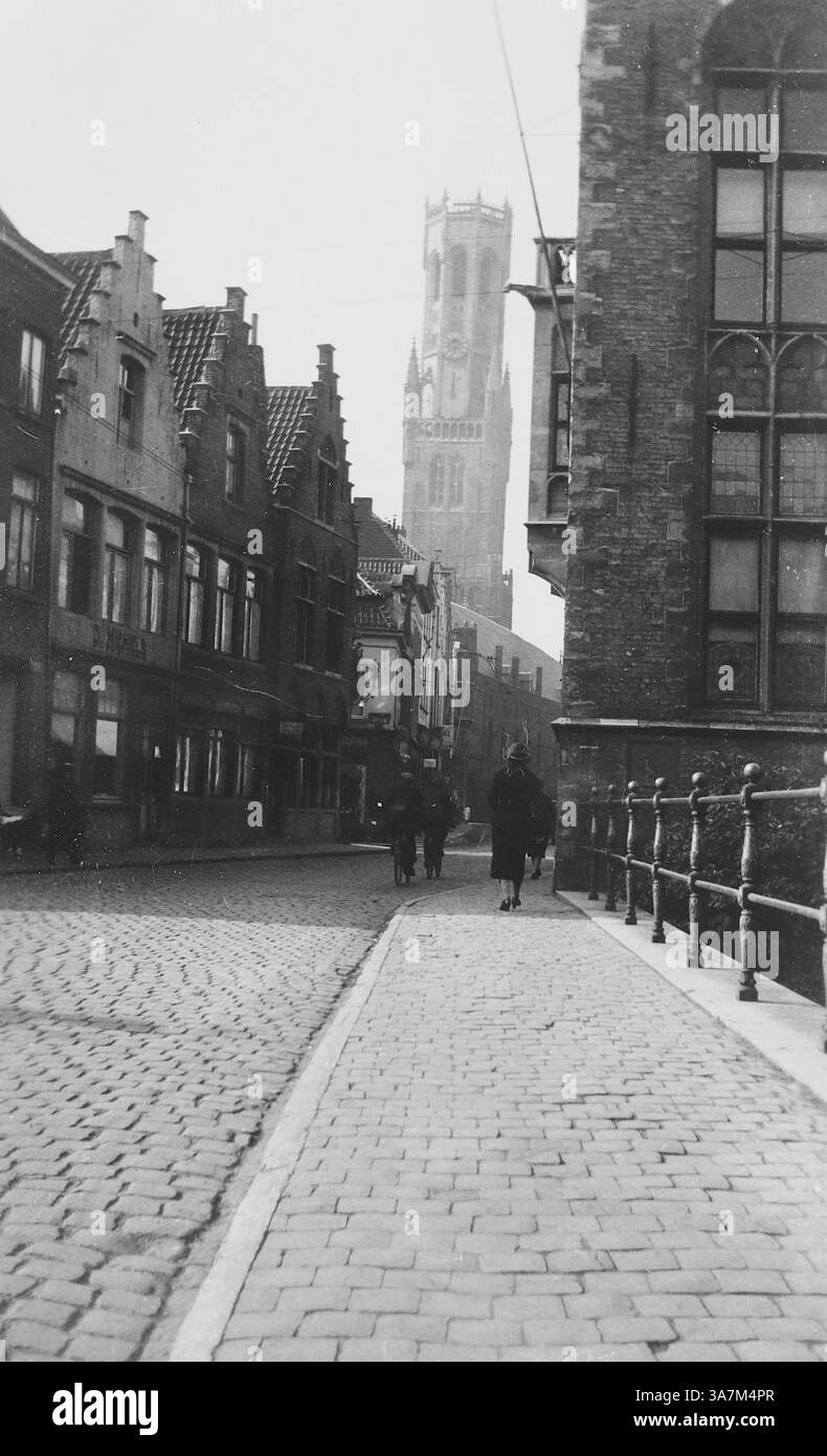 1932, une rue près du Quai Vert à Bruges, Belgique. En arrière-plan se trouve le grand beffroi de Bruges, ou Belfort, l'un des monuments les plus emblématiques de Bruges qui abrite un carillon avec 47 cloches qui sonnent encore à travers la ville. D'une collection de photographies amateurs non attribuées dans la plage de dates, 1929-1936, qui comprennent les vacances britanniques et européennes. La plupart des images originales étaient d'environ 3 ½ x 2 pouces. Banque D'Images