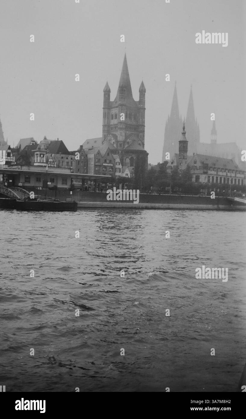 1936, Cologne, Allemagne, vue du Rhin. La tour la plus visible est l'église du Grand produit Martin. Cette église romane, avec sa grande tour pointue distinctive, était une caractéristique de la ligne d'horizon de Cologne à l'époque. Il se trouve près du Rhin et fait partie du patrimoine architectural de la ville. Dans le fond de l'image, se trouvent les flèches jumelles de la cathédrale de Cologne, partiellement obscurcies par la brume. D'une collection de photographies amateurs non attribuées dans la plage de dates, 1929-1936, qui comprennent les vacances britanniques et européennes. La plupart des images originales étaient d'environ 3 ½ x 2 pouces. Banque D'Images