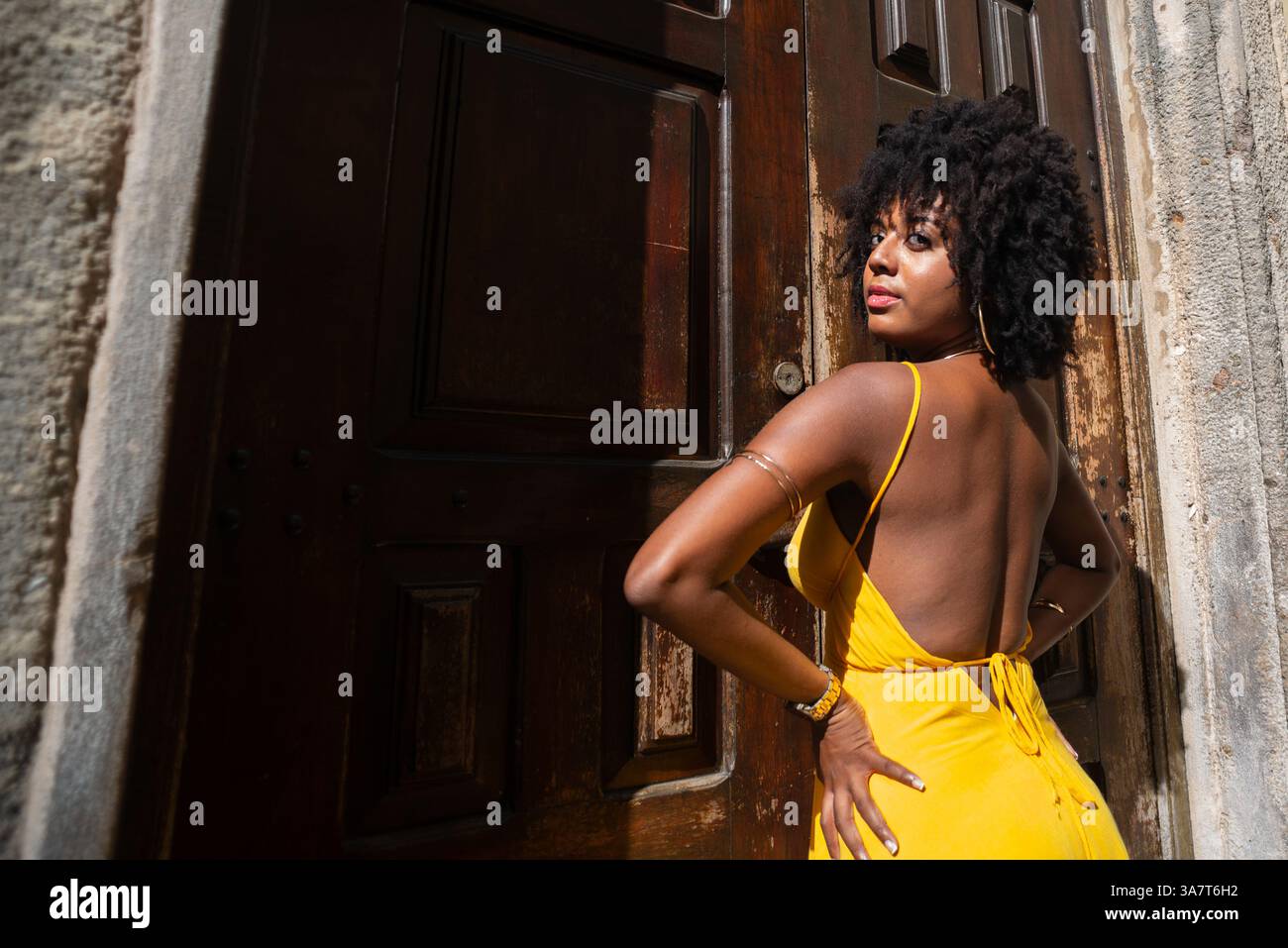 Portrait d'une belle femme portant une robe jaune debout par une vieille porte en bois brun. Concept de voyage de personne heureuse. Banque D'Images