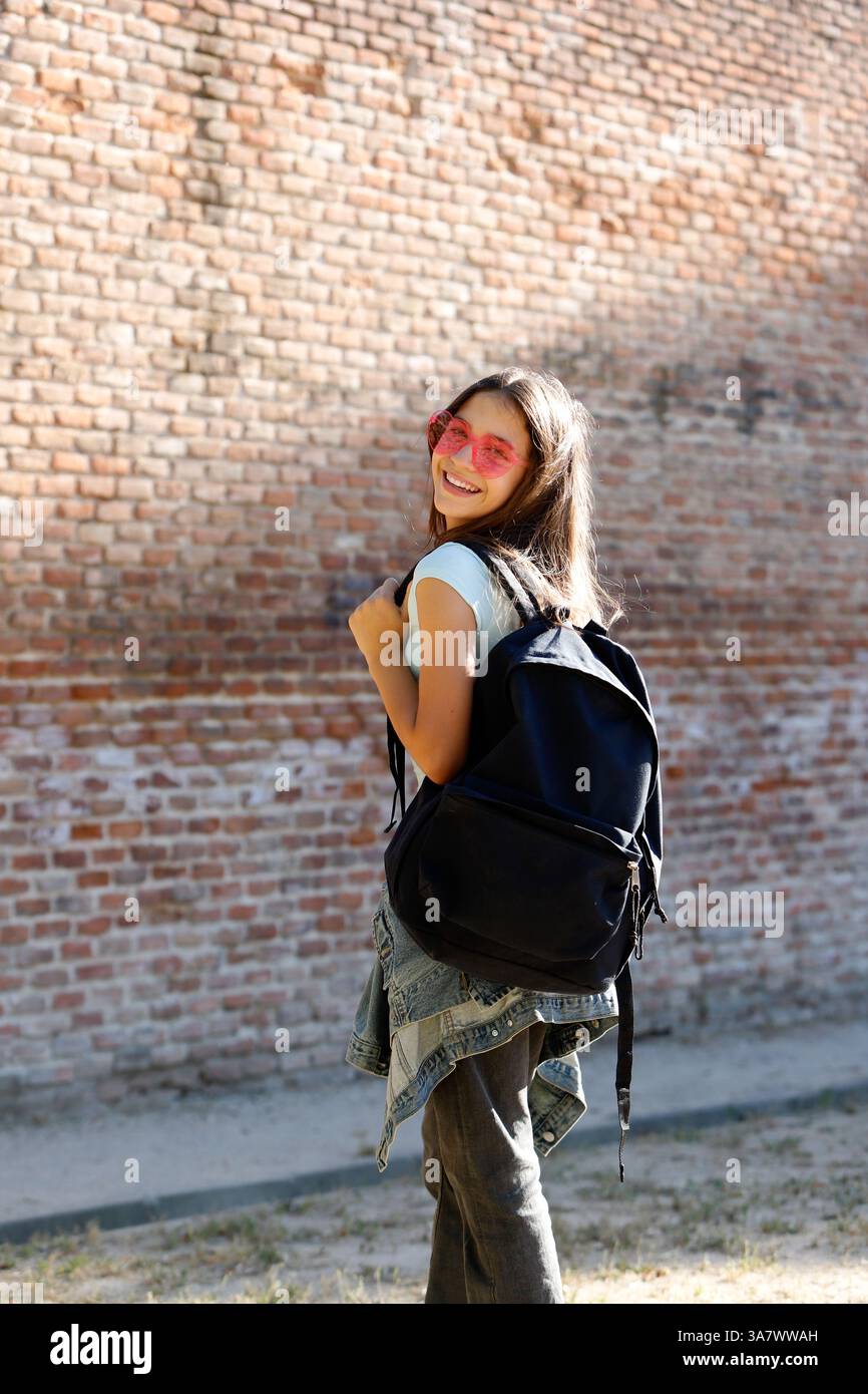 adolescent avec sac à dos et lunettes de soleil à la mode sur l'aire de jeux Banque D'Images