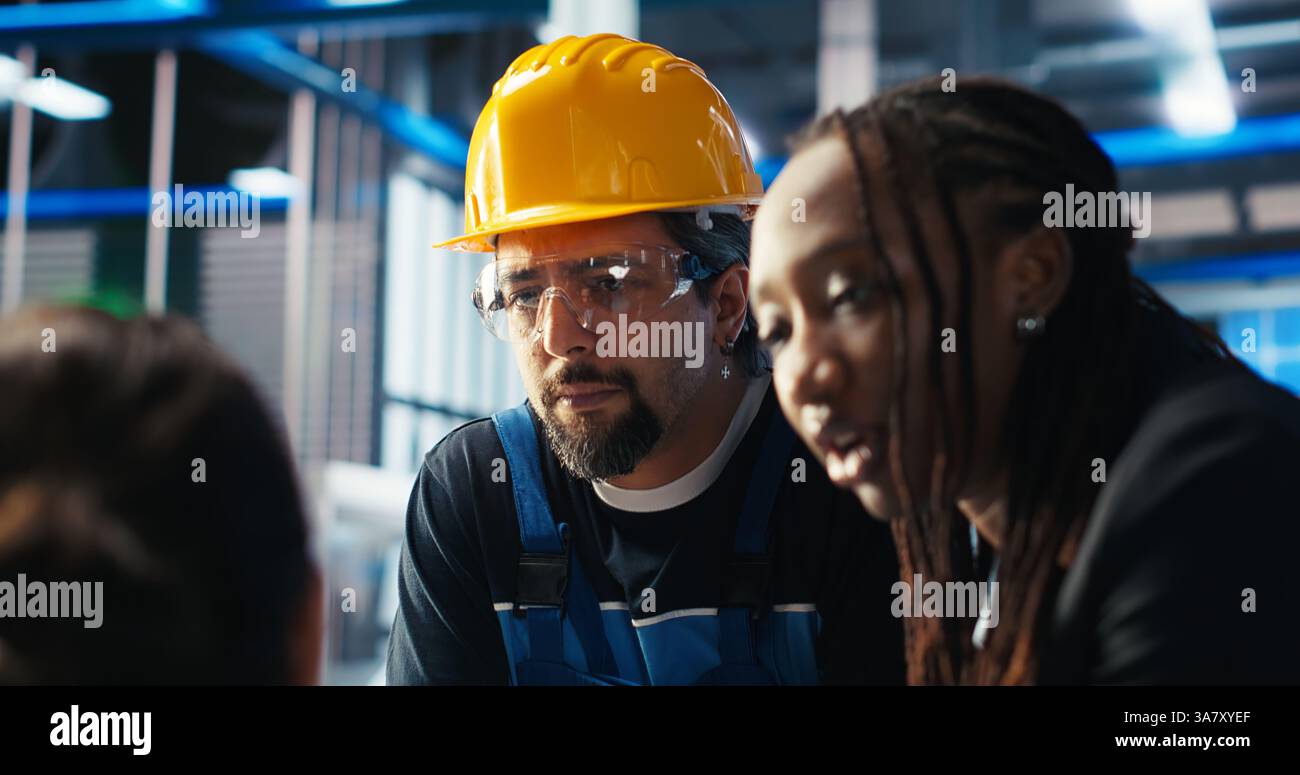 Directeur d'usine photovoltaïque donnant des tâches aux travailleurs, leur demandant d'ajuster les paramètres du système. Chef d'équipe expliquant aux employés comment optimiser l'approvisionnement en énergie dans l'usine de fabrication de panneaux solaires, caméra B. Banque D'Images