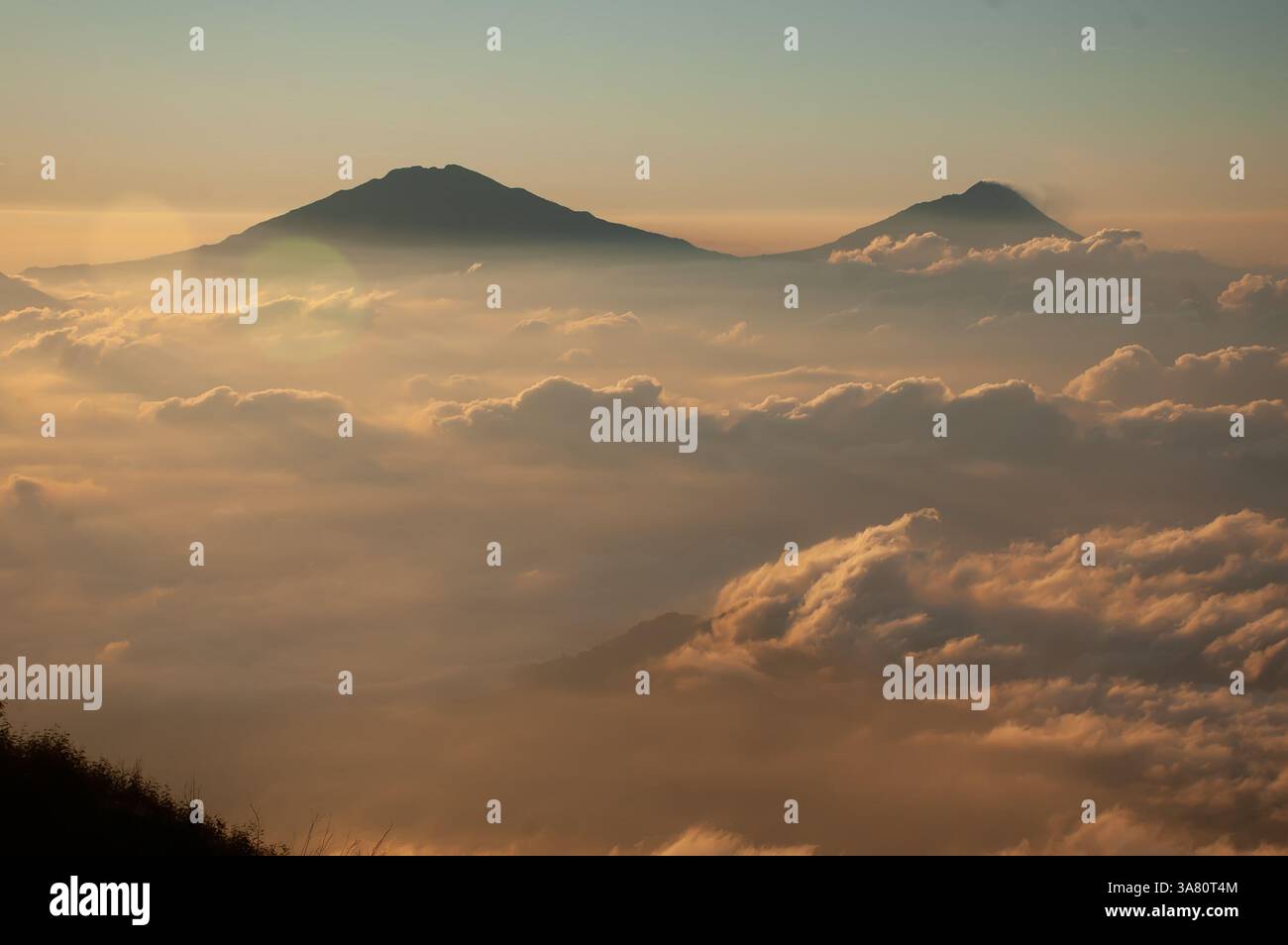 Une vue aérienne à couper le souffle des pics volcaniques s'élevant au-dessus d'une mer de nuages au lever du soleil Banque D'Images