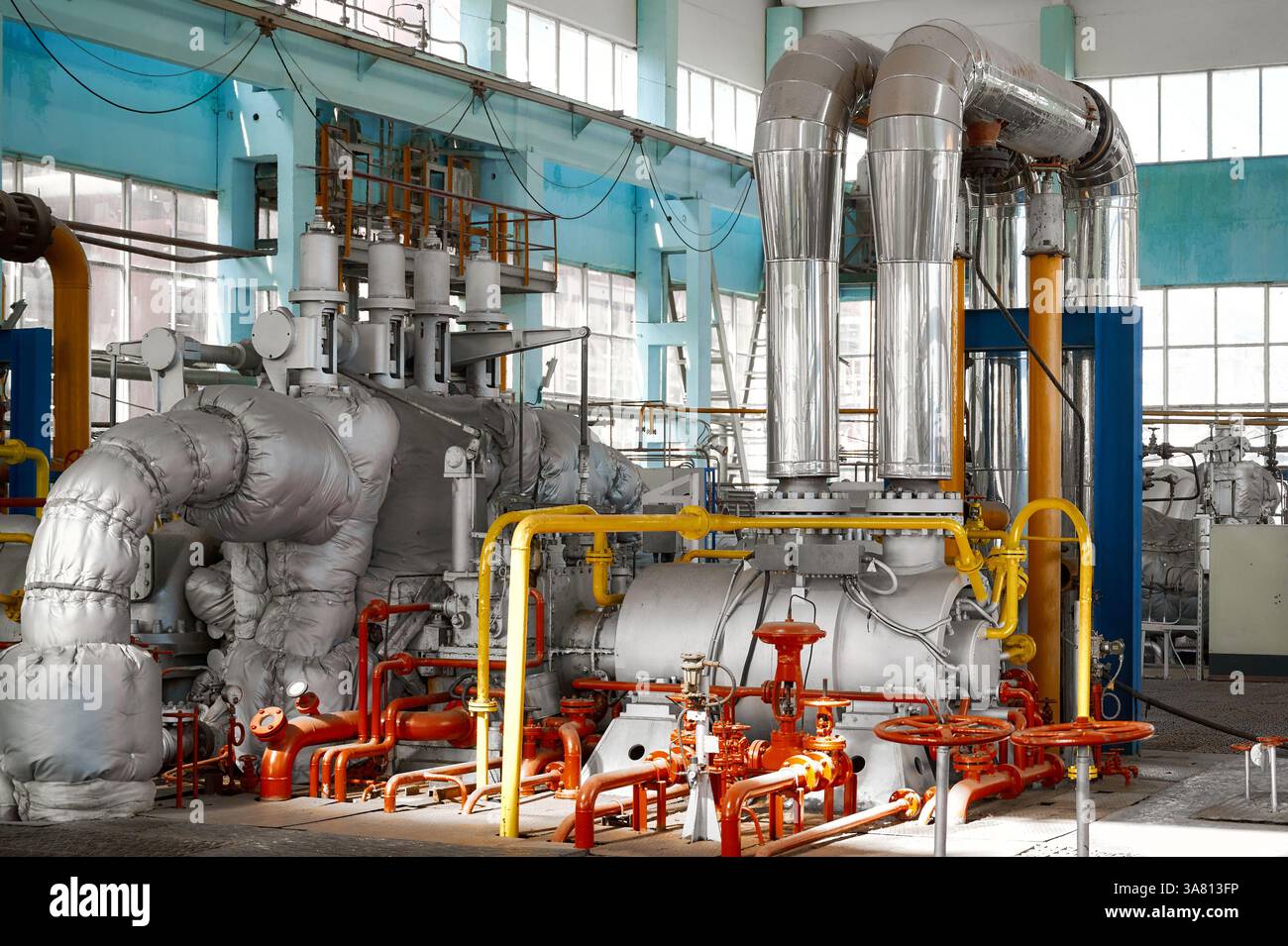 Pompe industrielle puissante fonctionnant dans une usine chimique avec des tuyaux et des machines vibrants pendant les heures de jour Banque D'Images