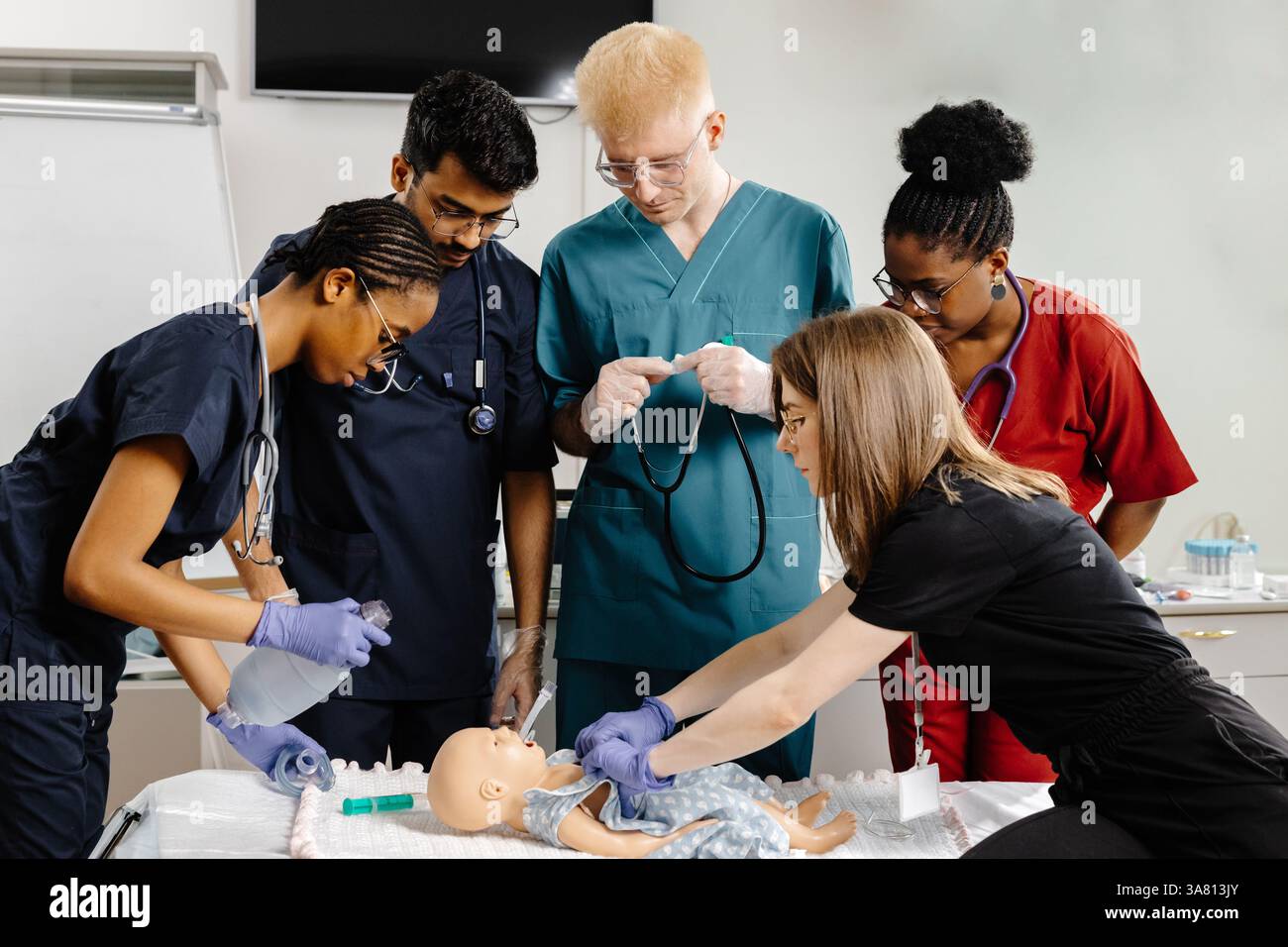 Groupe diversifié d'étudiants en médecine pratiquant l'intubation sur un mannequin de bébé, démontrant des compétences essentielles dans un environnement médical simulé Banque D'Images