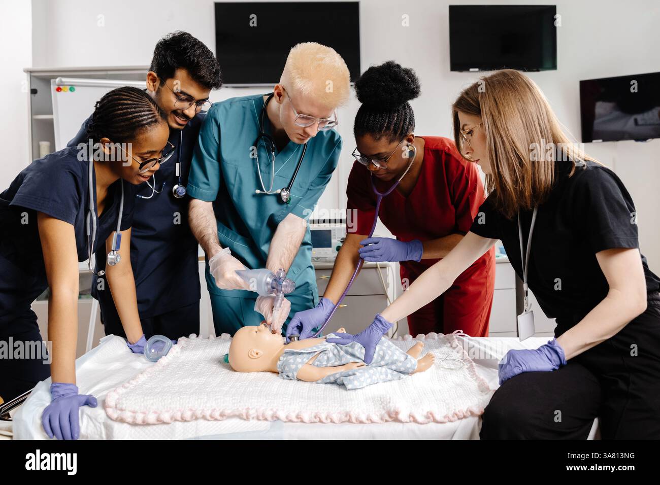Groupe diversifié d'étudiants en médecine pratiquant l'intubation sur un mannequin de bébé, démontrant des compétences essentielles dans un environnement médical simulé Banque D'Images