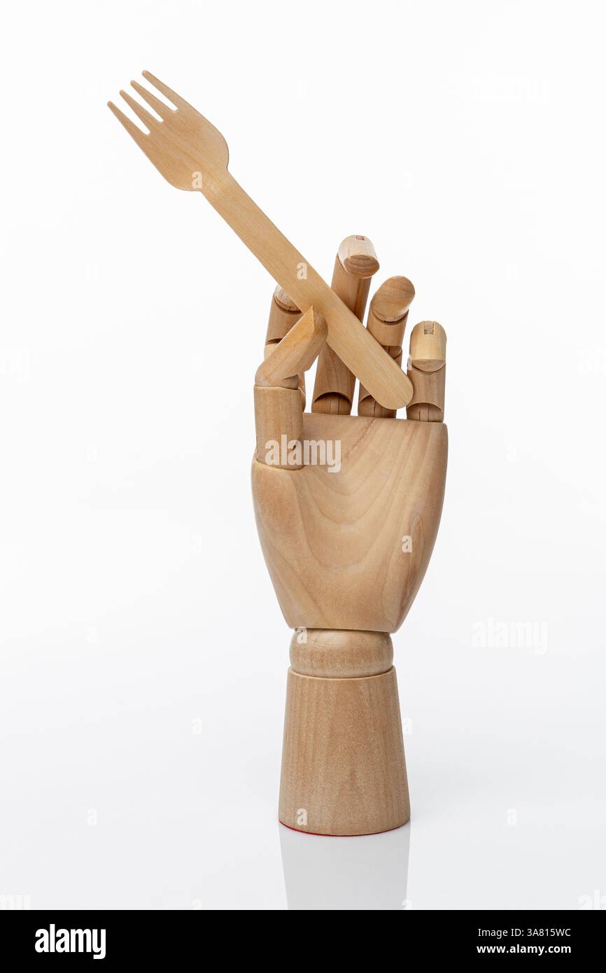Fourchette jetable en bois dans une main en bois d'un mannequin sur un fond blanc. Concept de nourriture saine et concept de produits naturels Banque D'Images