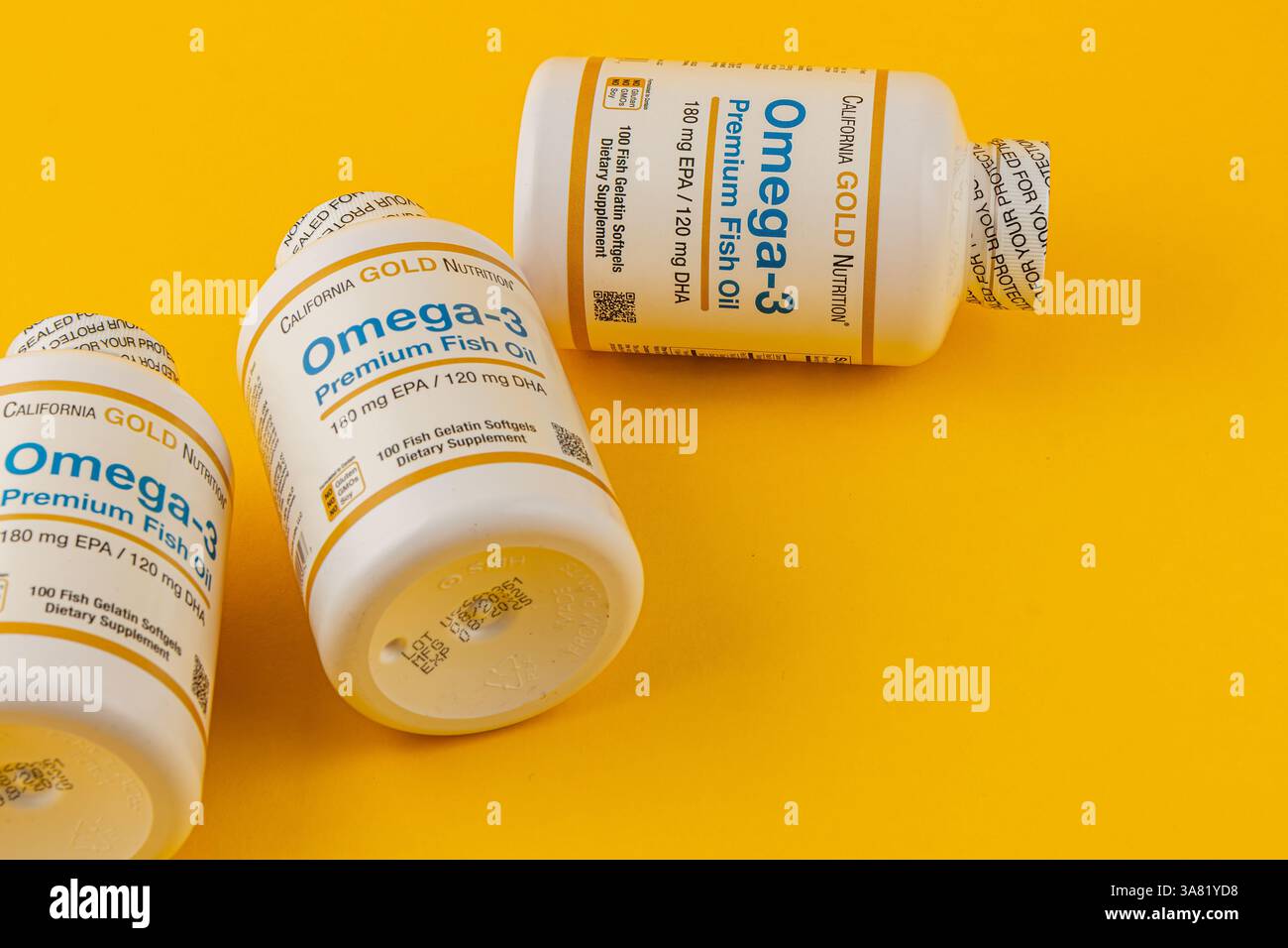 24.03.25 Lviv Ukraine trois bouteilles de suppléments d'huile de poisson de qualité supérieure oméga-3 sont placées sur une surface jaune vif. Chaque bouteille présente des détails sur Banque D'Images