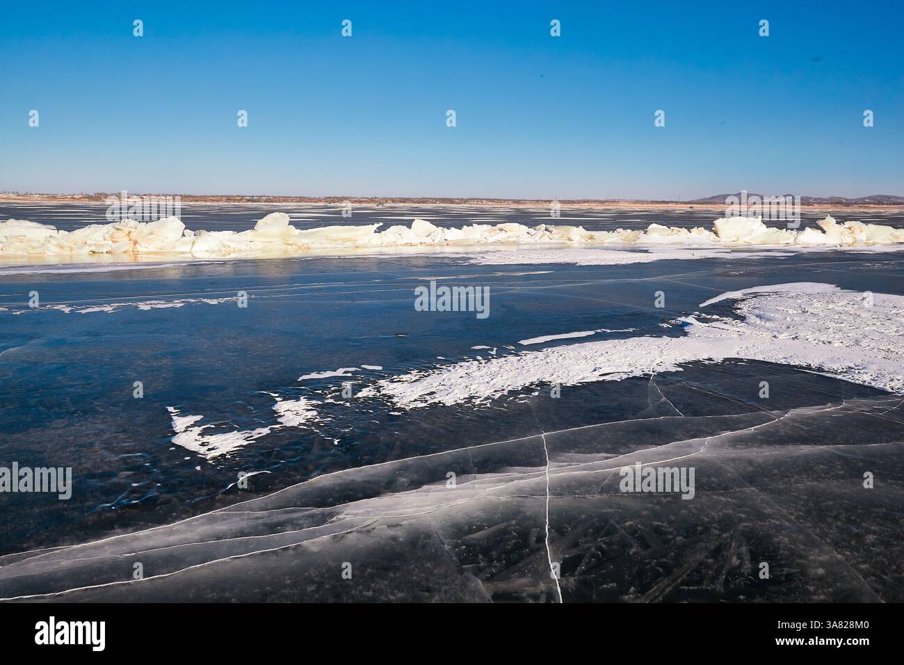Lac gelé avec chaîne de montagnes et village Banque D'Images