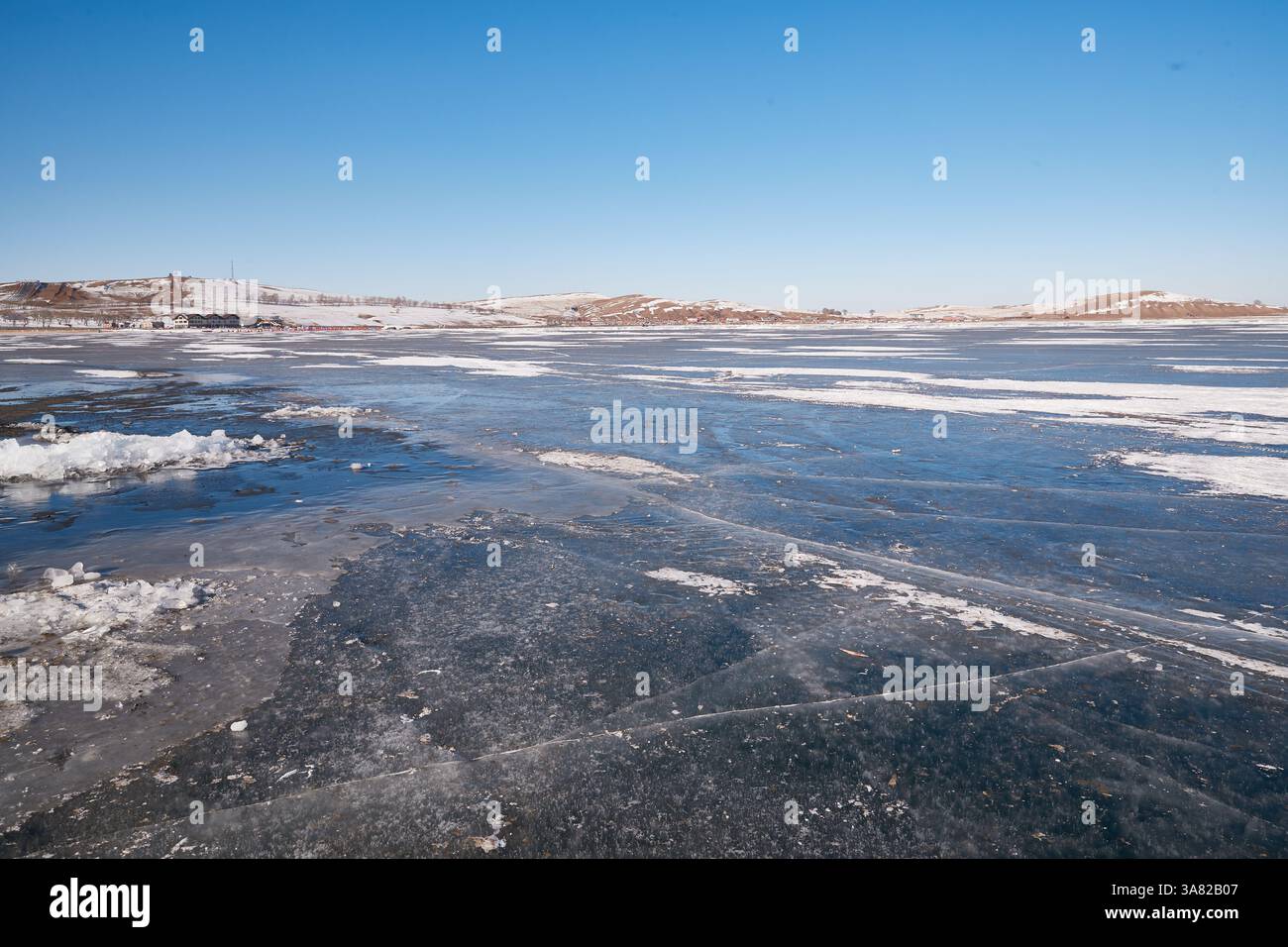 Lac gelé avec chaîne de montagnes et village Banque D'Images