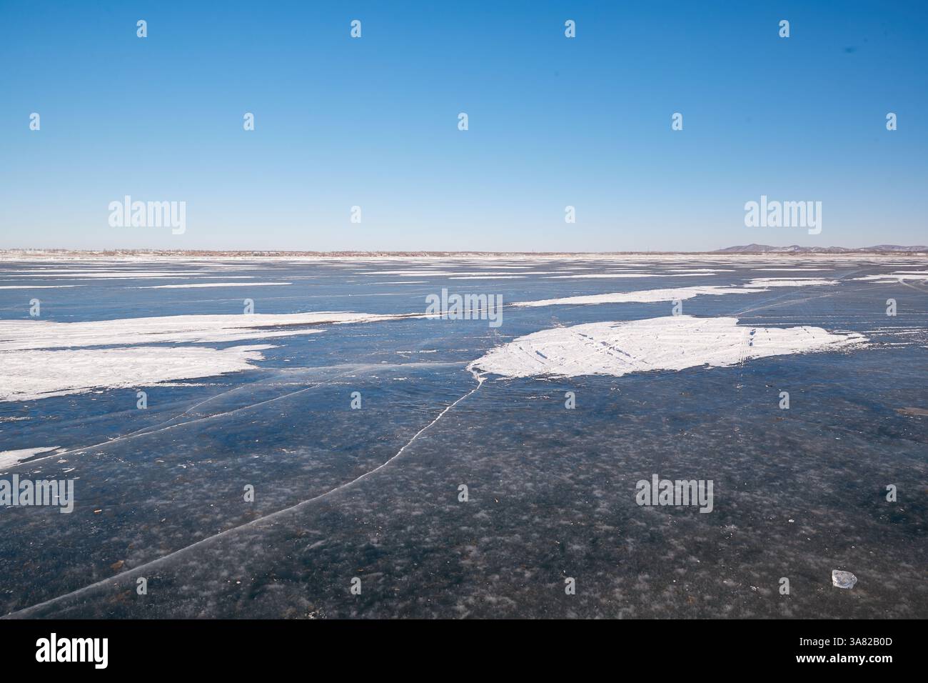 Lac gelé avec chaîne de montagnes et village Banque D'Images