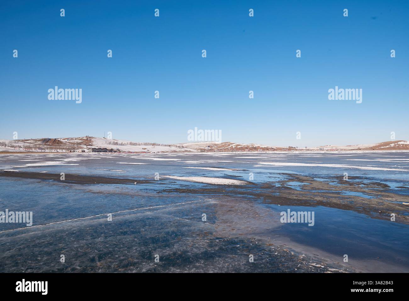 Lac gelé avec chaîne de montagnes et village Banque D'Images