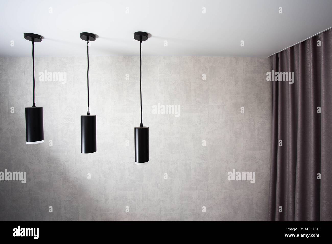 Lampes suspendues à diode noire modernes sur un plafond tendu blanc contre un mur avec un rideau. Copier l'espace pour le texte Banque D'Images