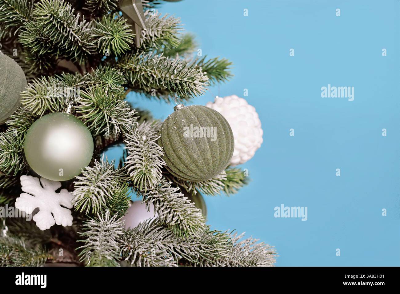 Arbre de Noël décoré avec boules d'ornement d'arbre vert sauge saisonnière sur fond bleu avec espace de copie Banque D'Images