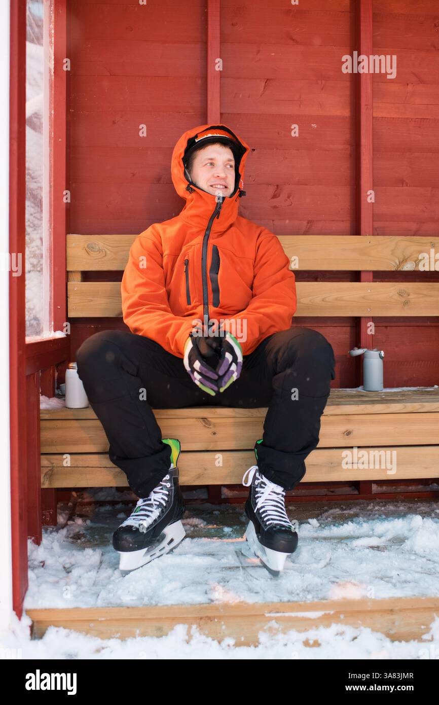 Homme assis sur les lignes latérales après le patinage sur glace en plein air en Suède Banque D'Images