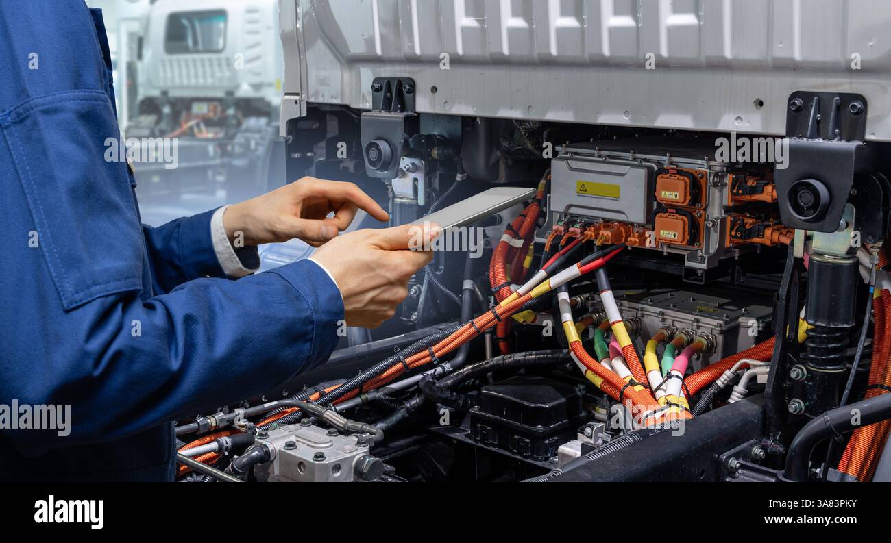 Technicien de service avec tablette numérique à côté du camion électrique. Entretien des véhicules électriques. Banque D'Images