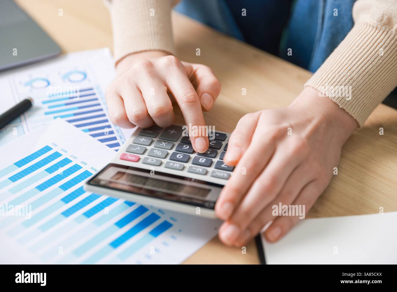 Budget. Femme avec la paperasse et la calculatrice au bureau en bois à l'intérieur, gros plan Banque D'Images