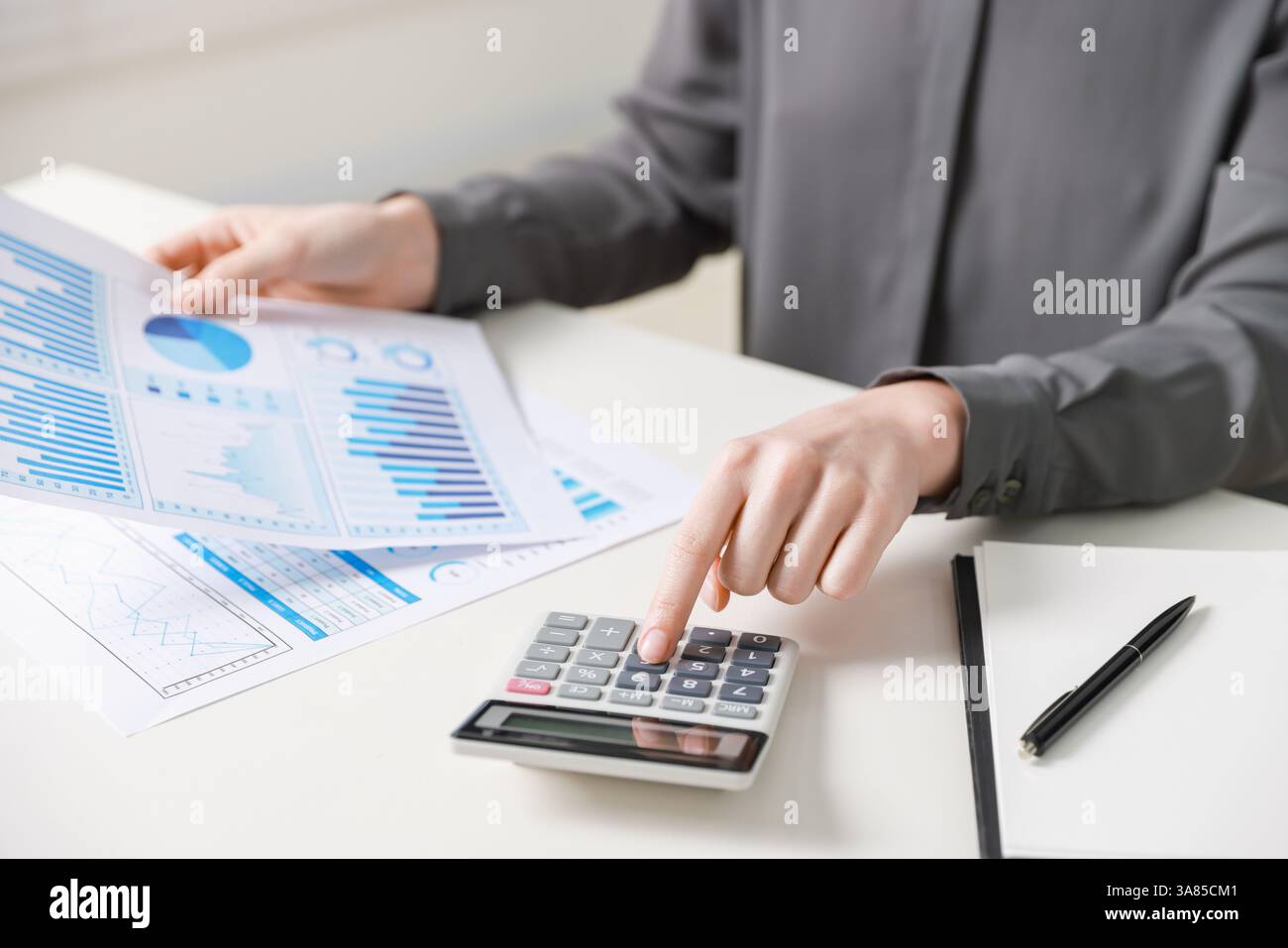 Budget. Femme avec la paperasse et la calculatrice au bureau blanc à l'intérieur, gros plan Banque D'Images