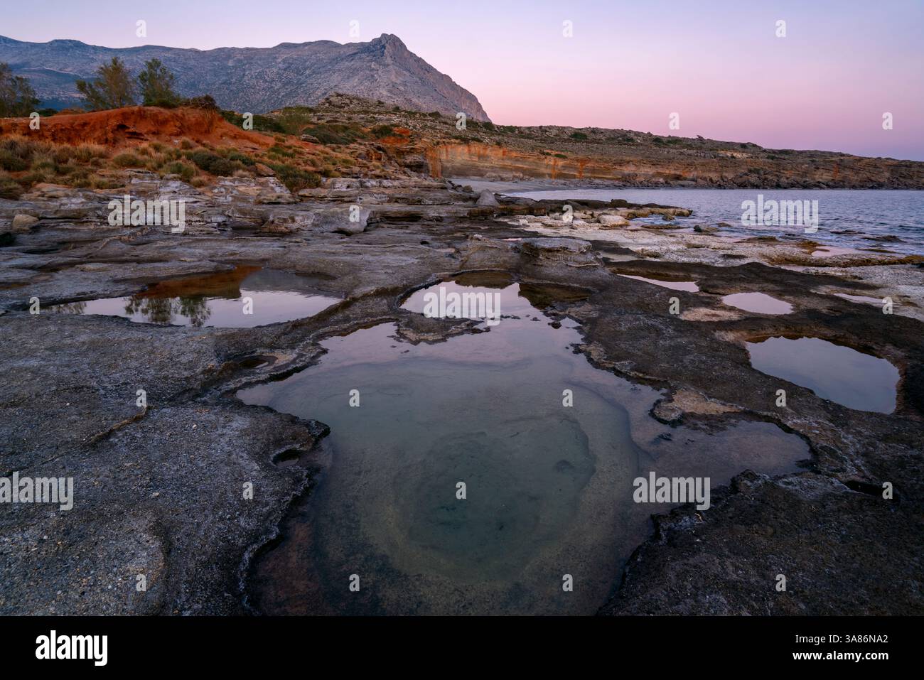 Plage d'Aspes, trous naturels dans les rochers pleins d'eau au coucher du soleil, avec la mer en arrière-plan, Grèce Banque D'Images