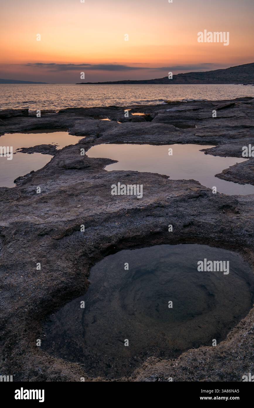 Trous naturels dans les rochers pleins d'eau au coucher du soleil, avec la mer en arrière-plan, Grèce Banque D'Images